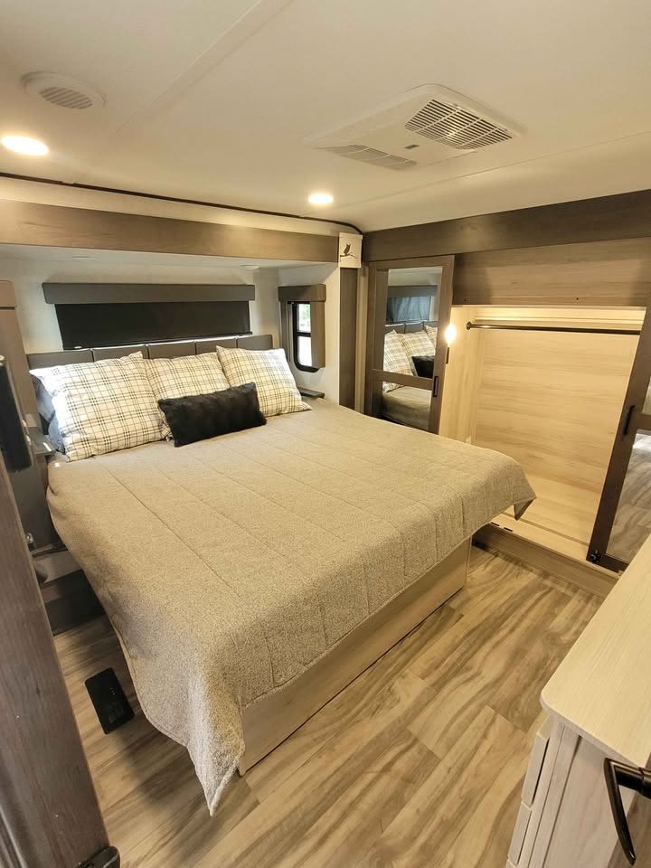 Experience comfort in this stylish RV rental bedroom. Features a large bed, modern decor, ceiling AC, and wood-look floor.. Alliance Valor 2022
