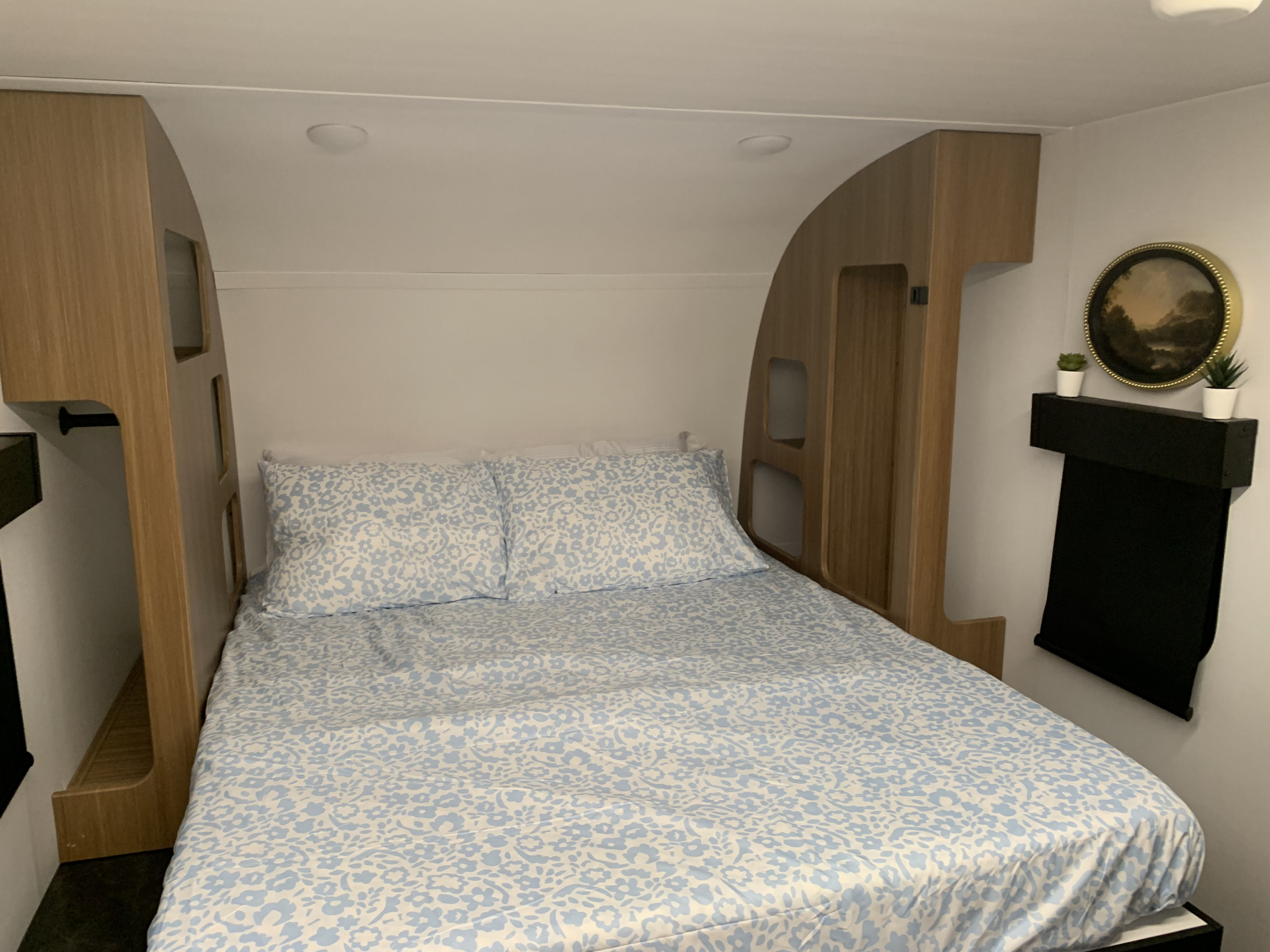 Cozy RV rental bedroom with a floral patterned bed, built-in wooden storage, and minimalist decor, perfect for travel.. Keystone Reign 18 RB 2025