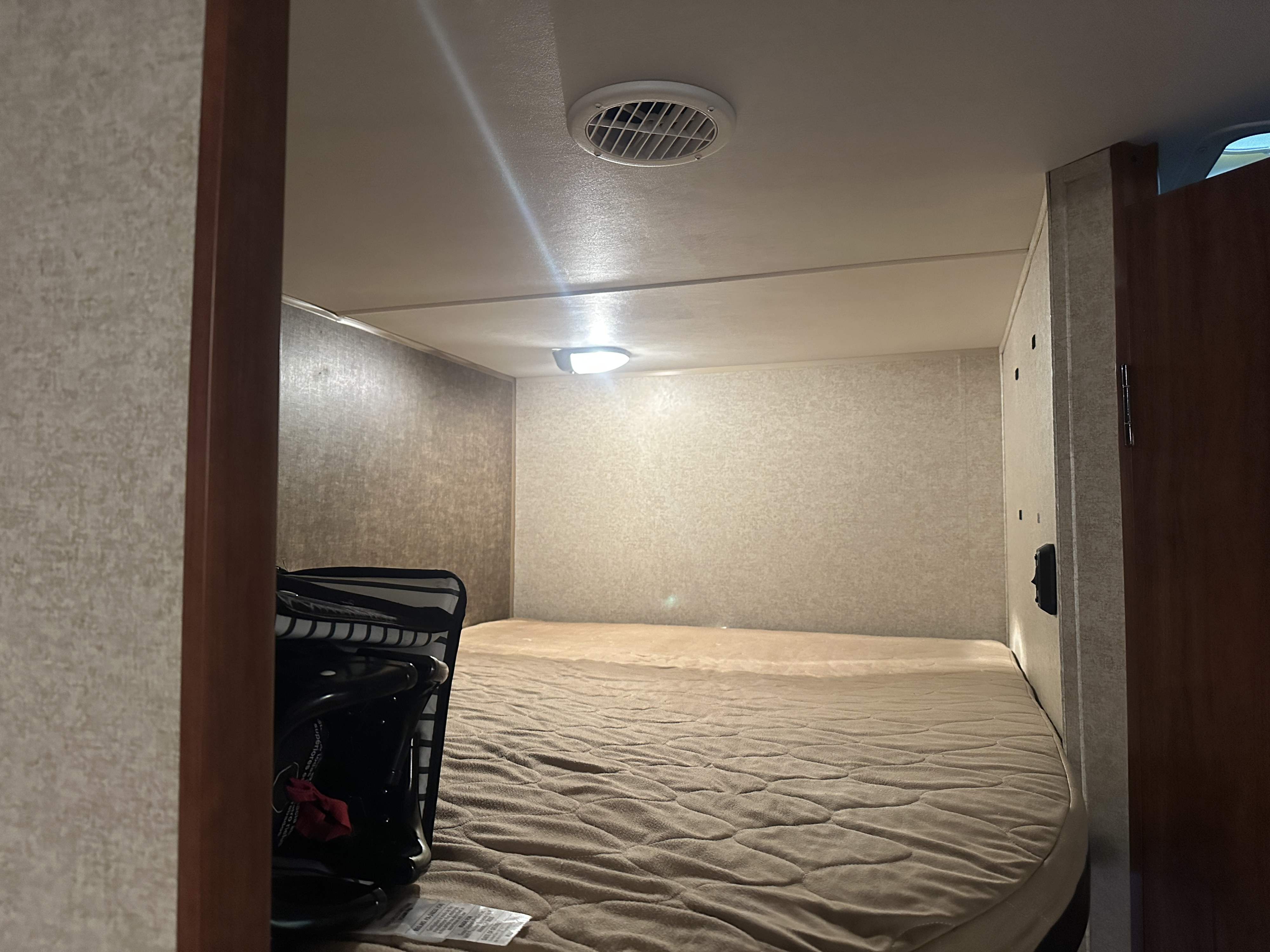 Cozy RV rental bedroom with a comfy mattress, overhead vent, and light. Perfect for a restful trip.. Heartland RVs Trail Runner 2014