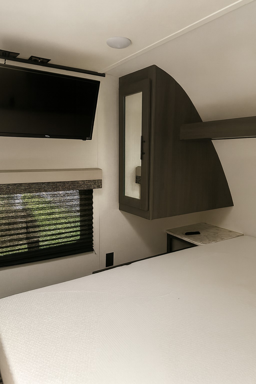 This modern RV rental bedroom offers a comfortable bed, TV, window, and storage for your journey.. Dutchmen Colorado 29BH 2022