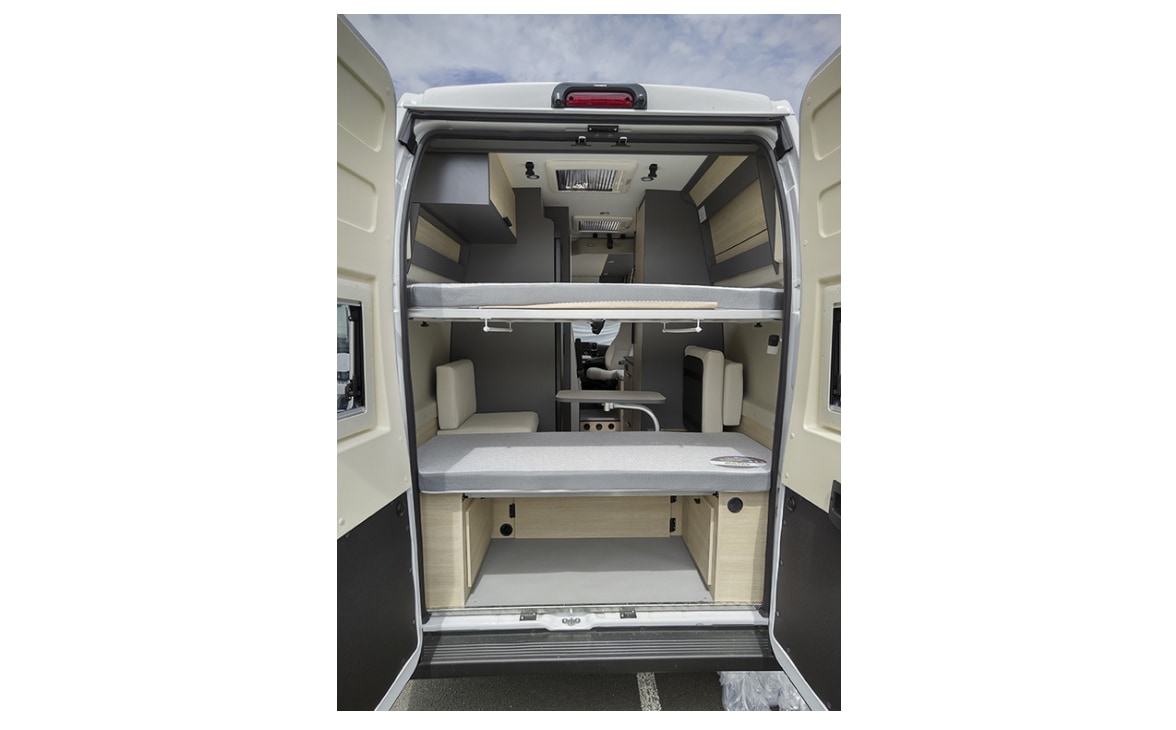 Compact RV rental interior featuring modular bunk beds and seating, viewed from the open rear doors of a campervan.. Dreamer Camper Five 2026