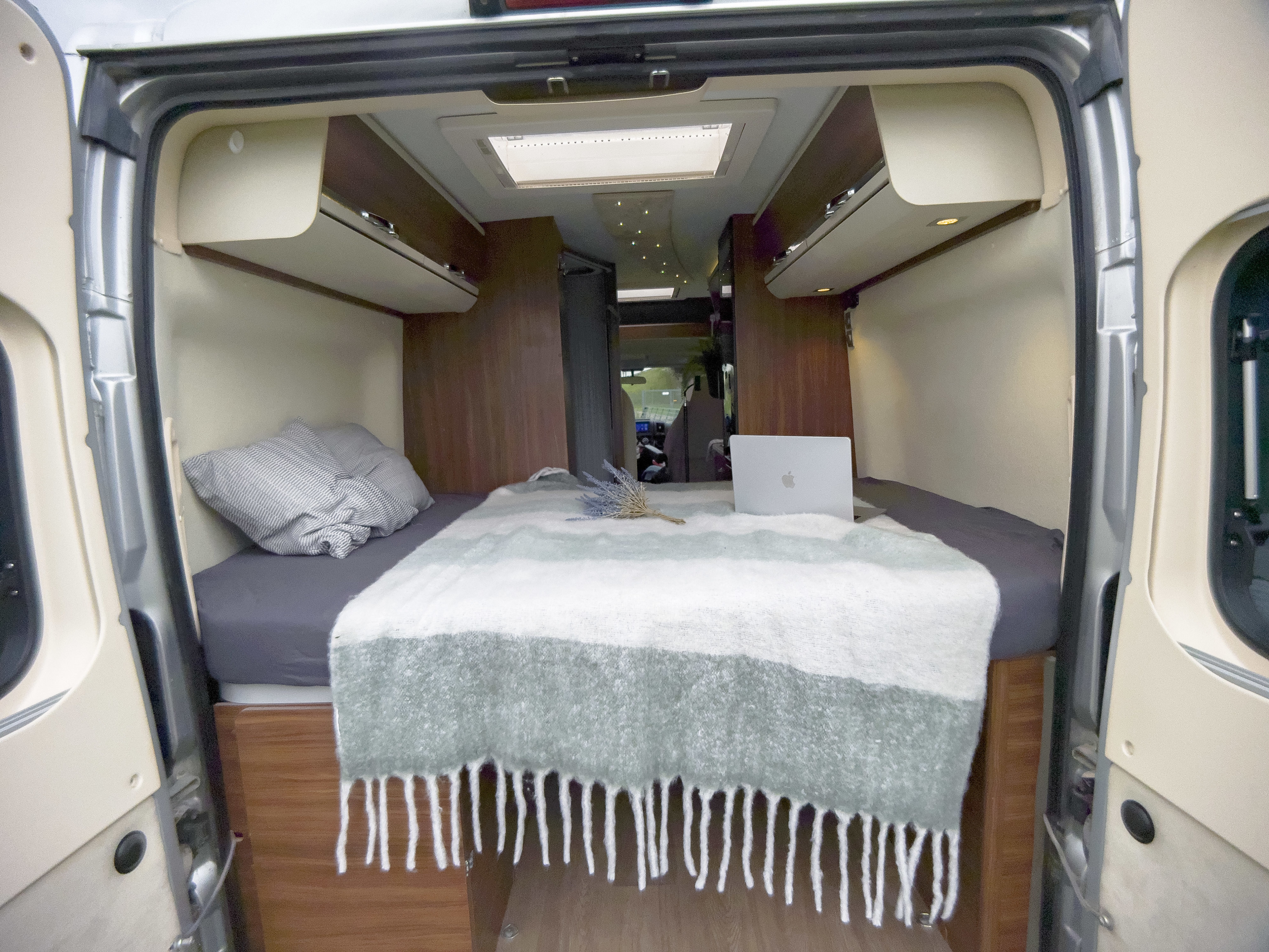 Cozy RV rental interior, showing a made bed with a laptop, lavender, storage, and skylight. Ready for travel.. Adria Twin 600 SP 2017