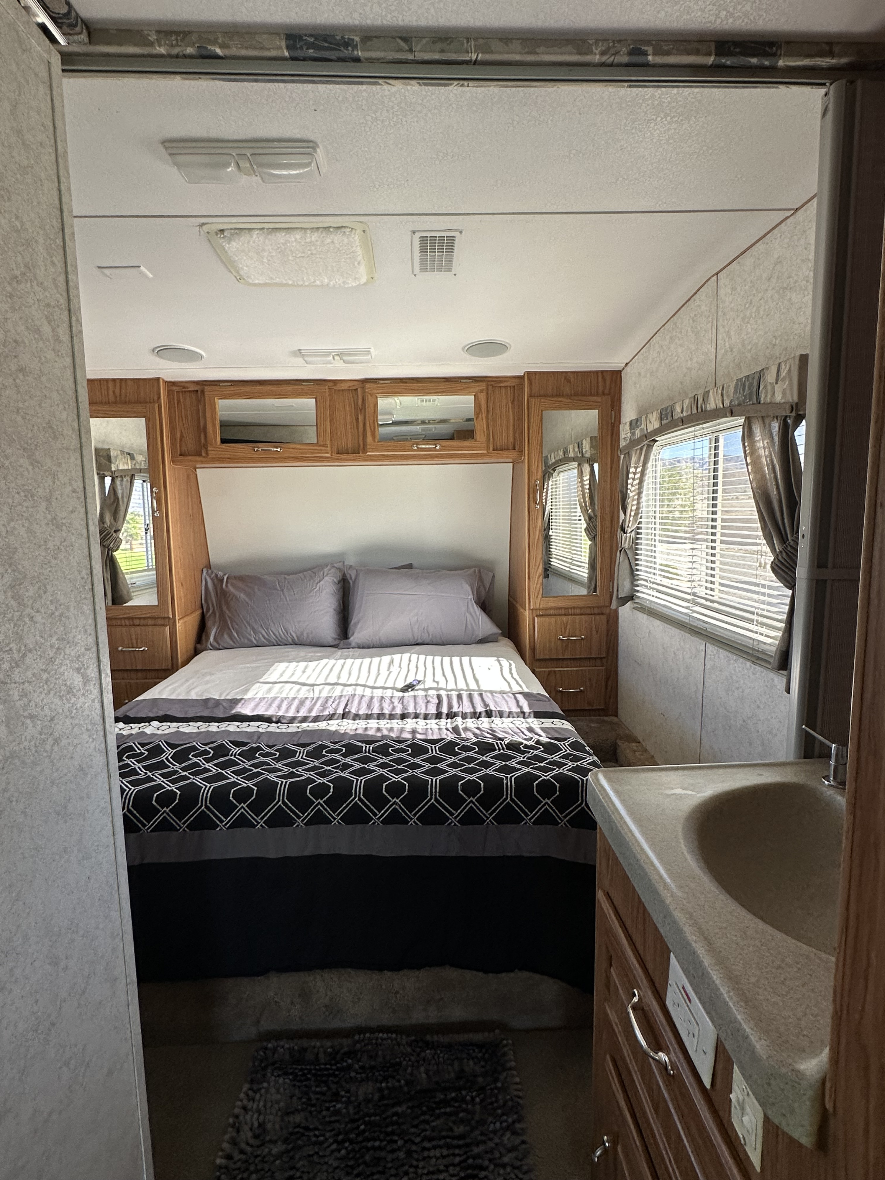 Cozy RV rental bedroom interior with bed, built-in cabinetry, and sink. Perfect for your next adventure!. Weekend Warrior 40 2005