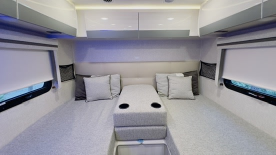Comfortable RV rental bedroom interior with twin beds, central storage, and window blinds for a cozy sleep space.. Thor Compass 2024
