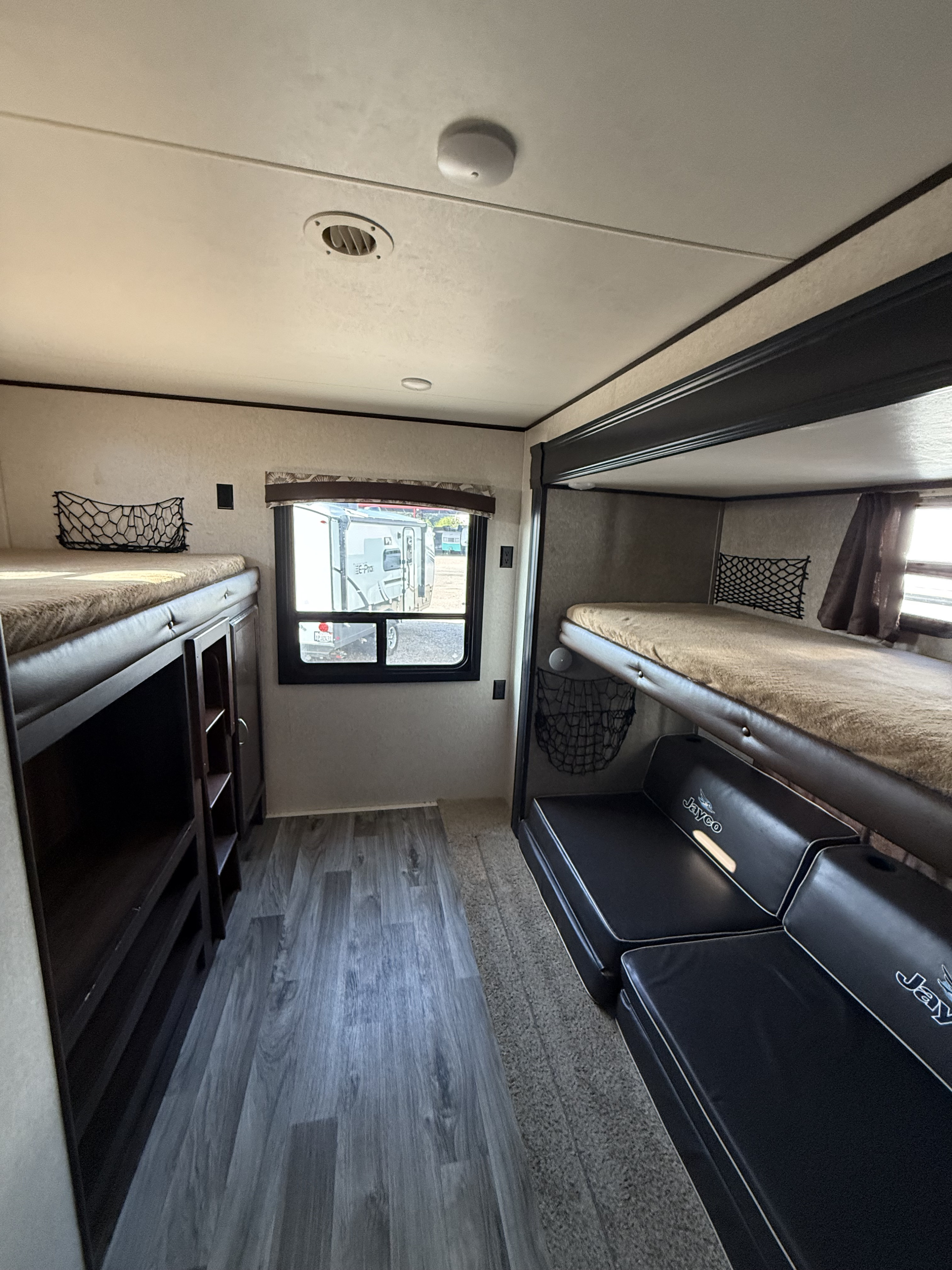 Spacious RV rental bunkhouse interior featuring multiple beds, storage shelves, and cushioned seating, perfect for family adventures.. Jayco Jay Flight 2018