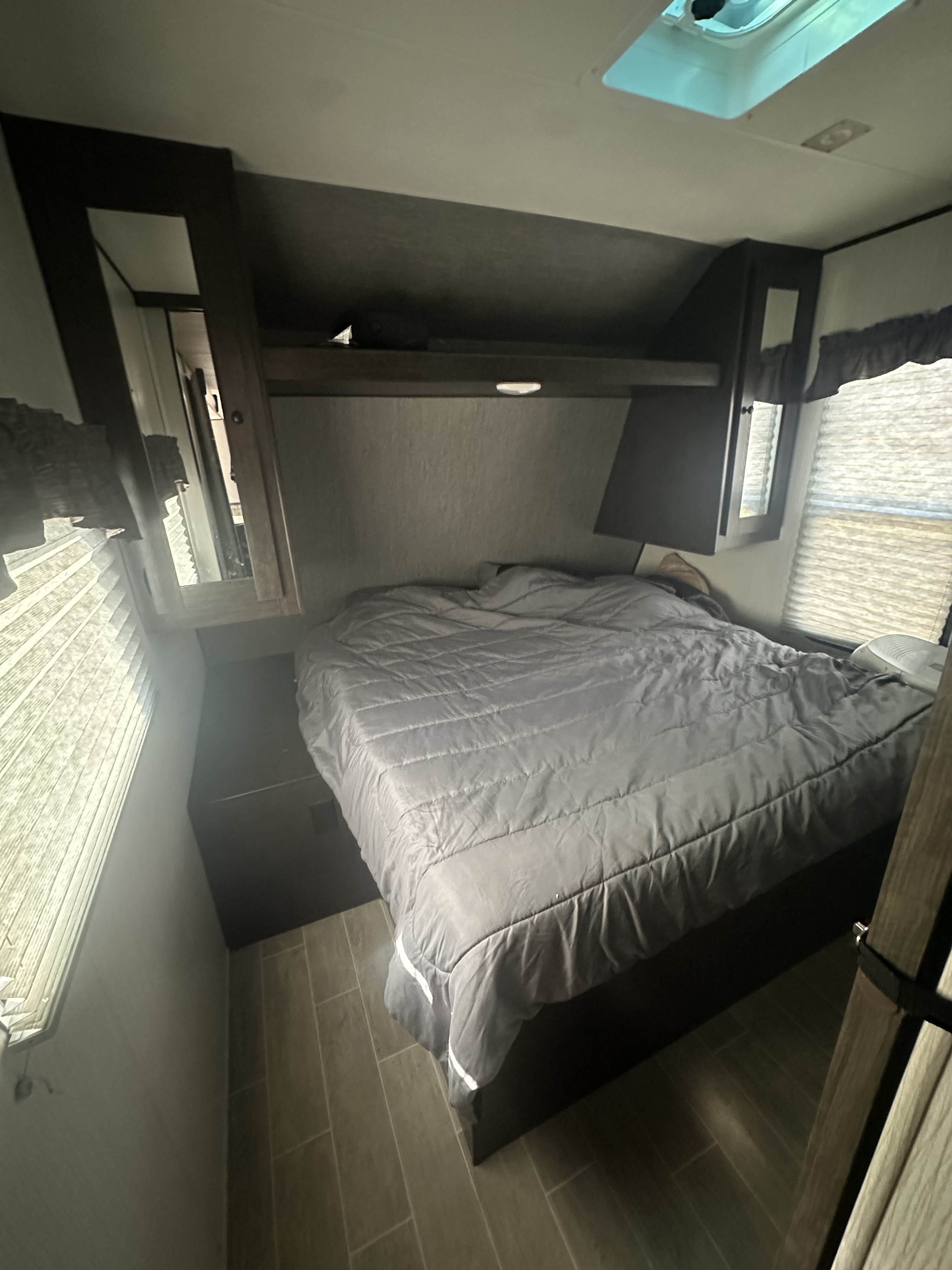 Cozy RV rental bedroom with a comfortable bed, overhead cabinets, windows, and blinds, ideal for travel.. Heartland RVs Trail Runner 2020