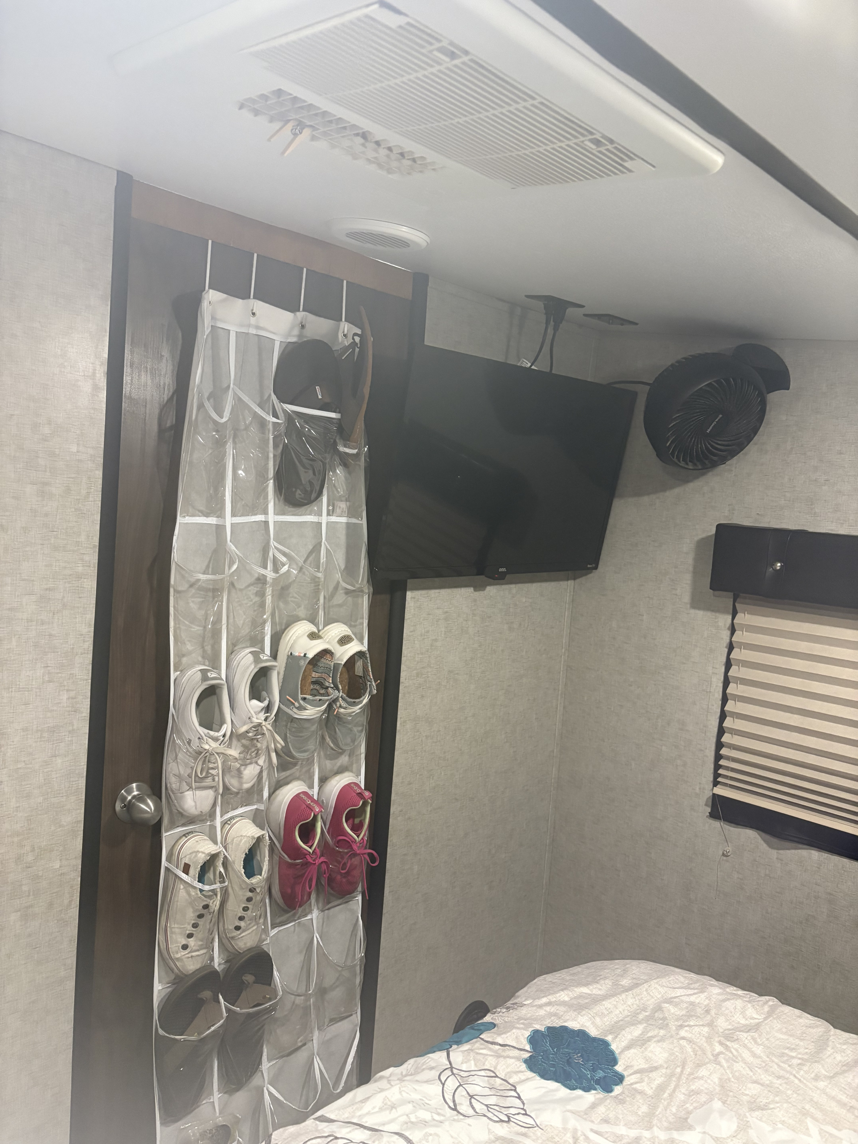 RV rental bedroom: over-door shoe organizer, mounted TV, fan, AC unit, and bed. Efficient storage for compact living.. Forest River Cherokee Wolf Pack 2018