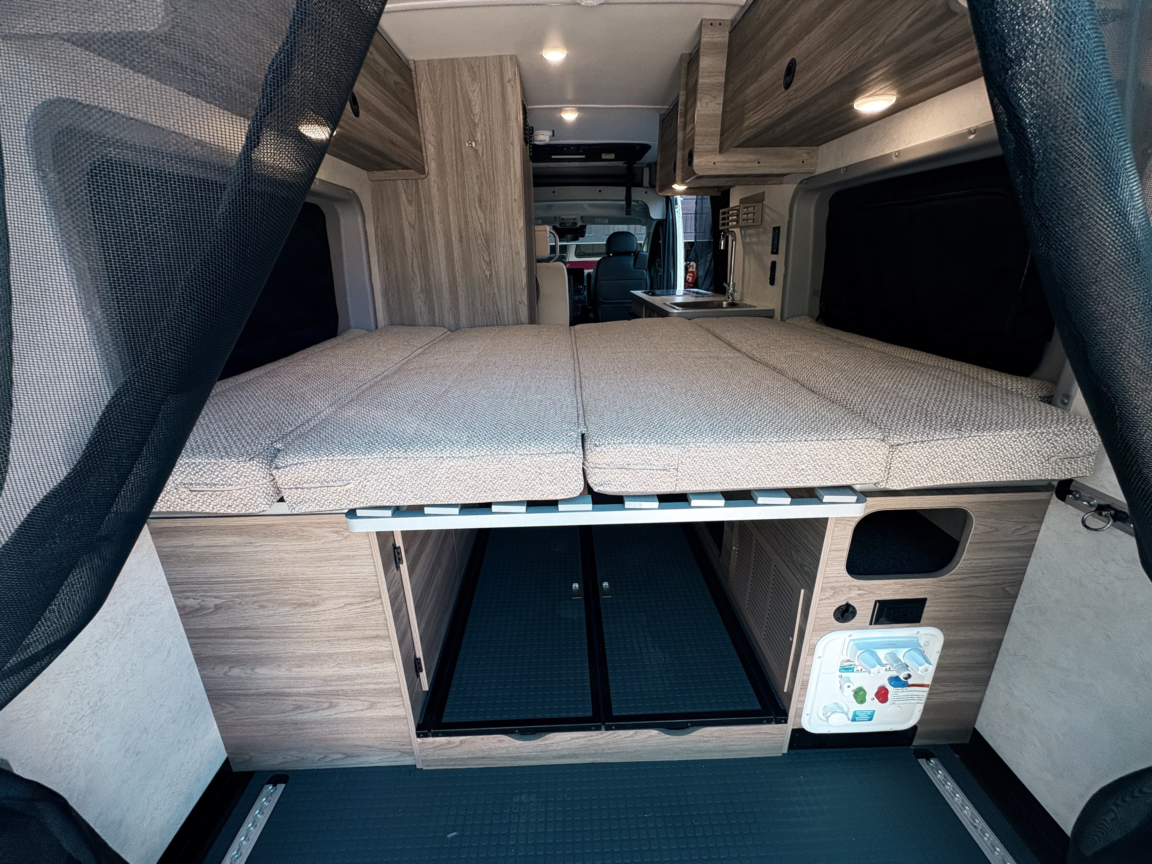 Spacious RV rental interior showing a comfy bed, under-bed storage, and accessible utility panel in this well-equipped camper van.. 3c6mrvjg9se527066 Winnebago 2026