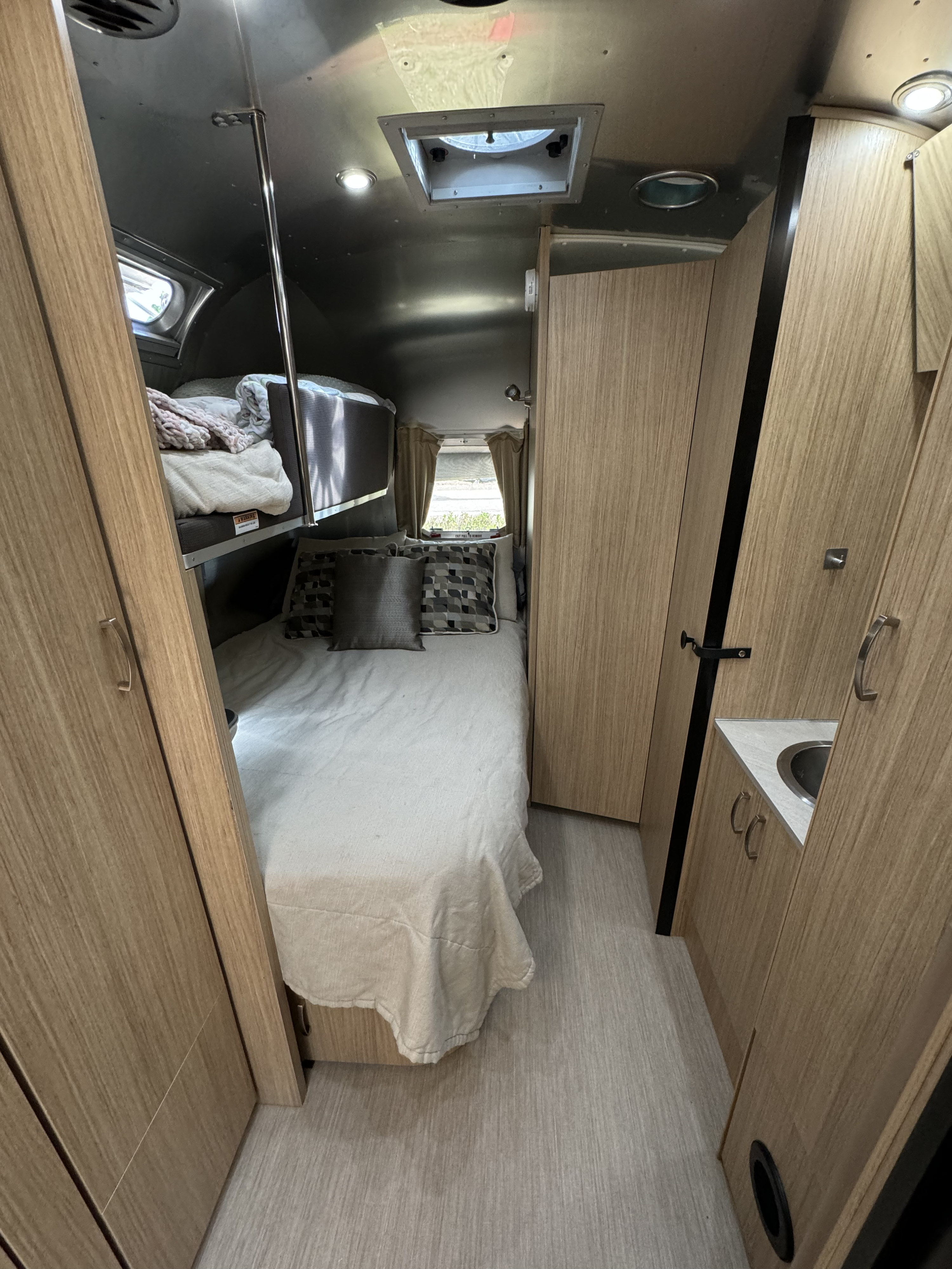 Compact rv rental interior showing bunk beds, a main bed, and a small sink in a cabinet.. Airstream Flying Cloud 2018