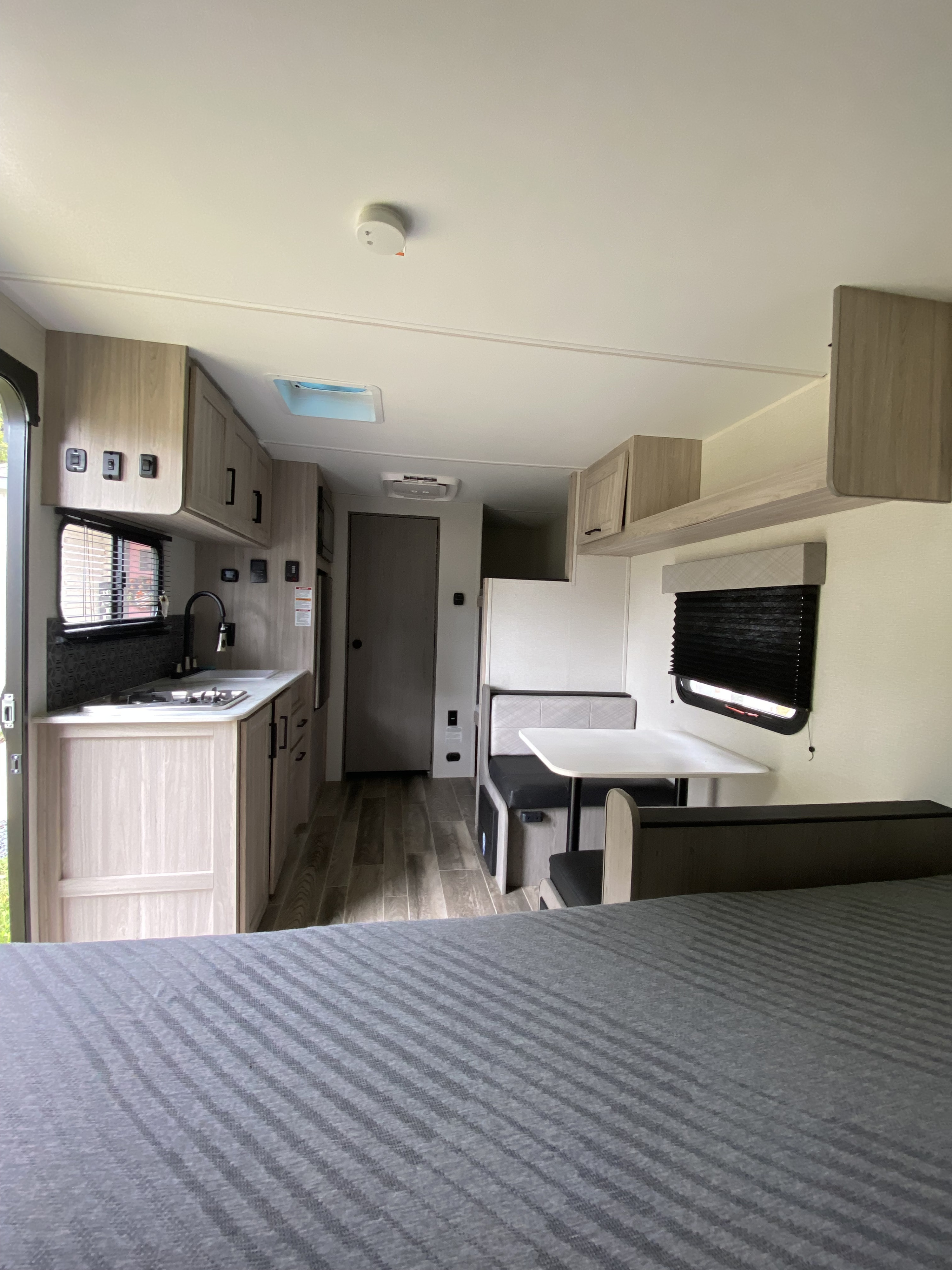 This rv rental features a well-equipped kitchen, a comfortable dinette with a table, and a bed in a modern interior.. Heartland RVs Mallard 2025
