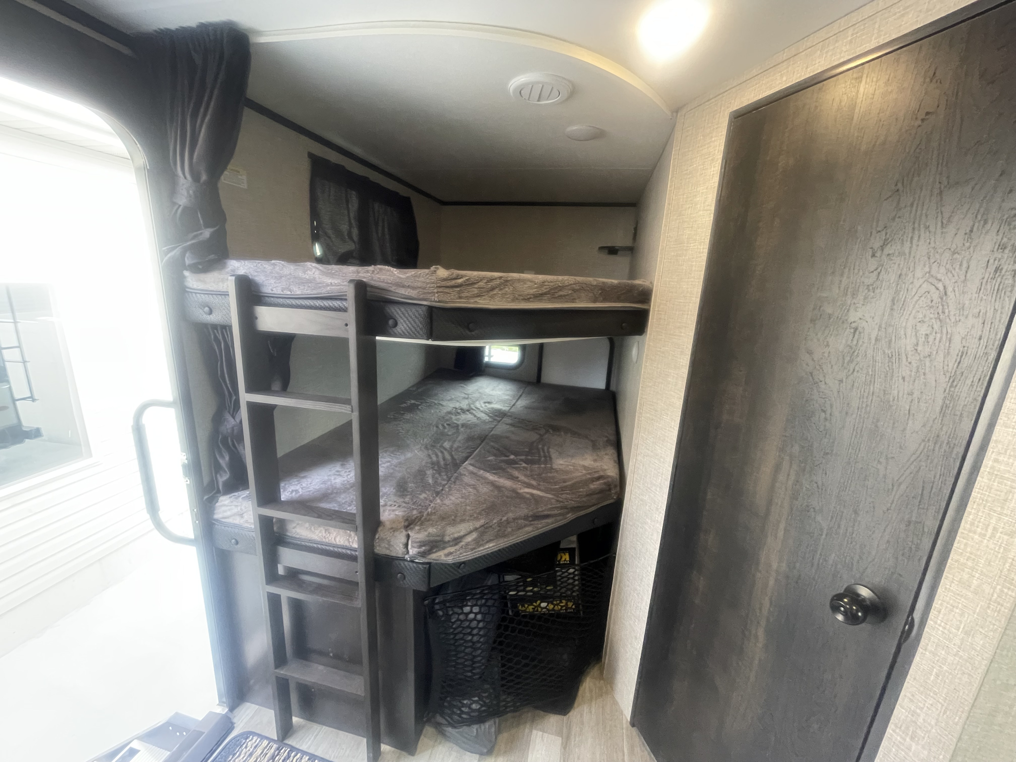 Comfortable bunk beds with ladder & storage in this rv rental, with a bright entryway visible.. Jayco Jay Feather 2022
