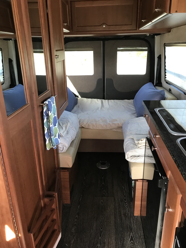 RV rental camper van interior: comfortable bed, compact kitchen with sink, and wooden storage cabinets.. Roadtrek RS Adventurous XL 2017