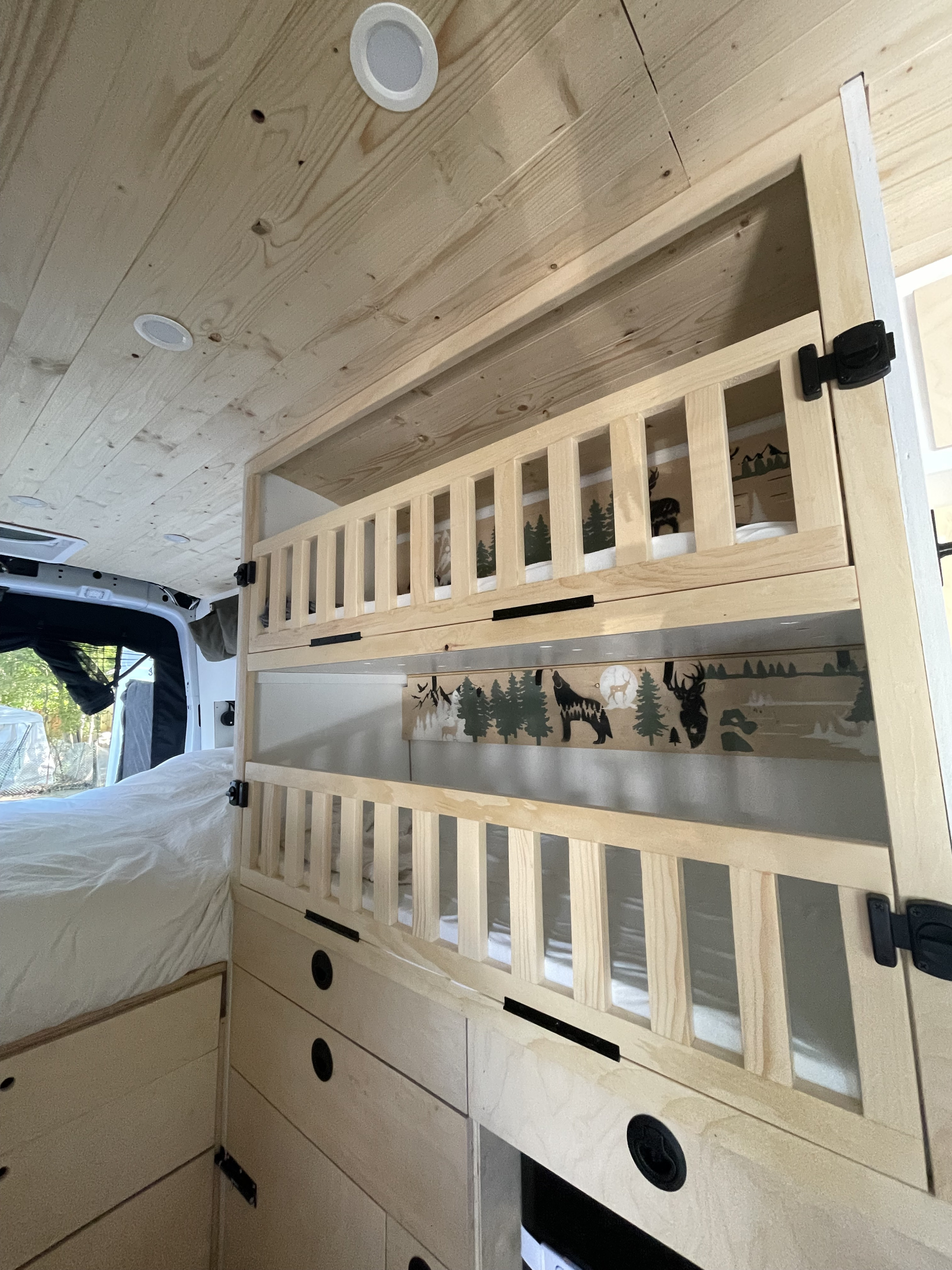 Cozy RV rental interior featuring wooden bunk beds with a nature mural and wood-paneled ceiling, perfect for family adventures.. Ford Transit 2019