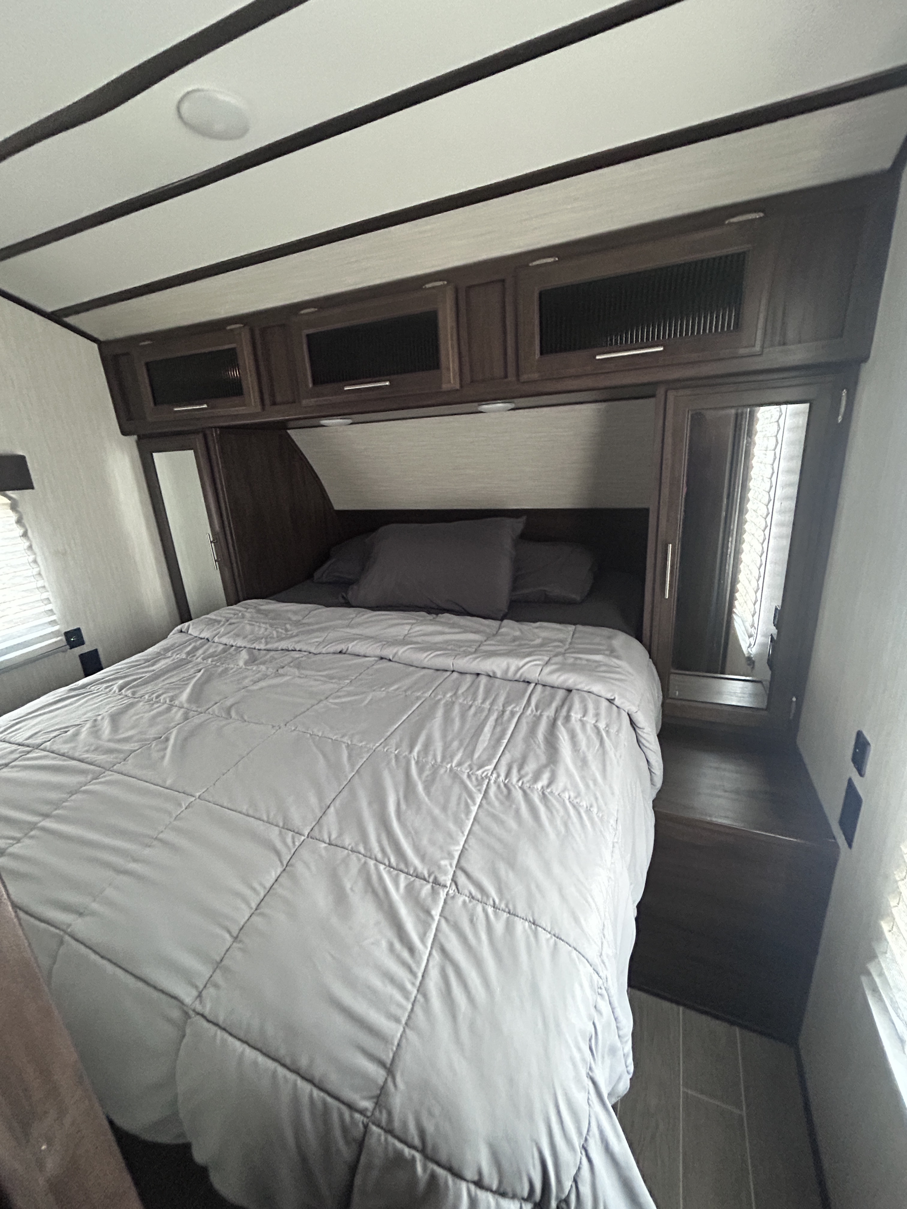 RV rental bedroom with grey-quilted bed, dark wood overhead cabinets & mirrored storage. Perfect for your next adventure.. Escape Trailer Alpha Wolf 2020