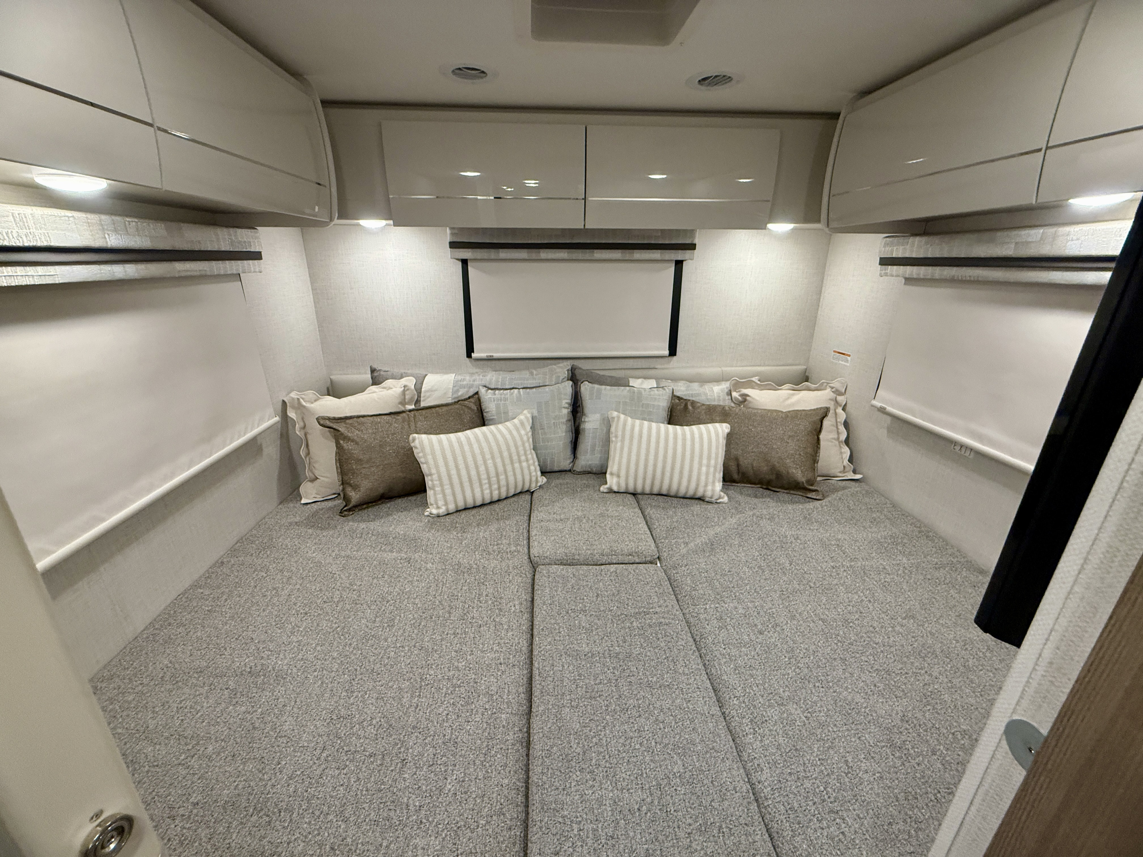 Cozy rv rental interior with a comfortable bed, pillows, overhead storage, and window blinds. Perfect for travel.. Thor Motorcoach Vegas 2025