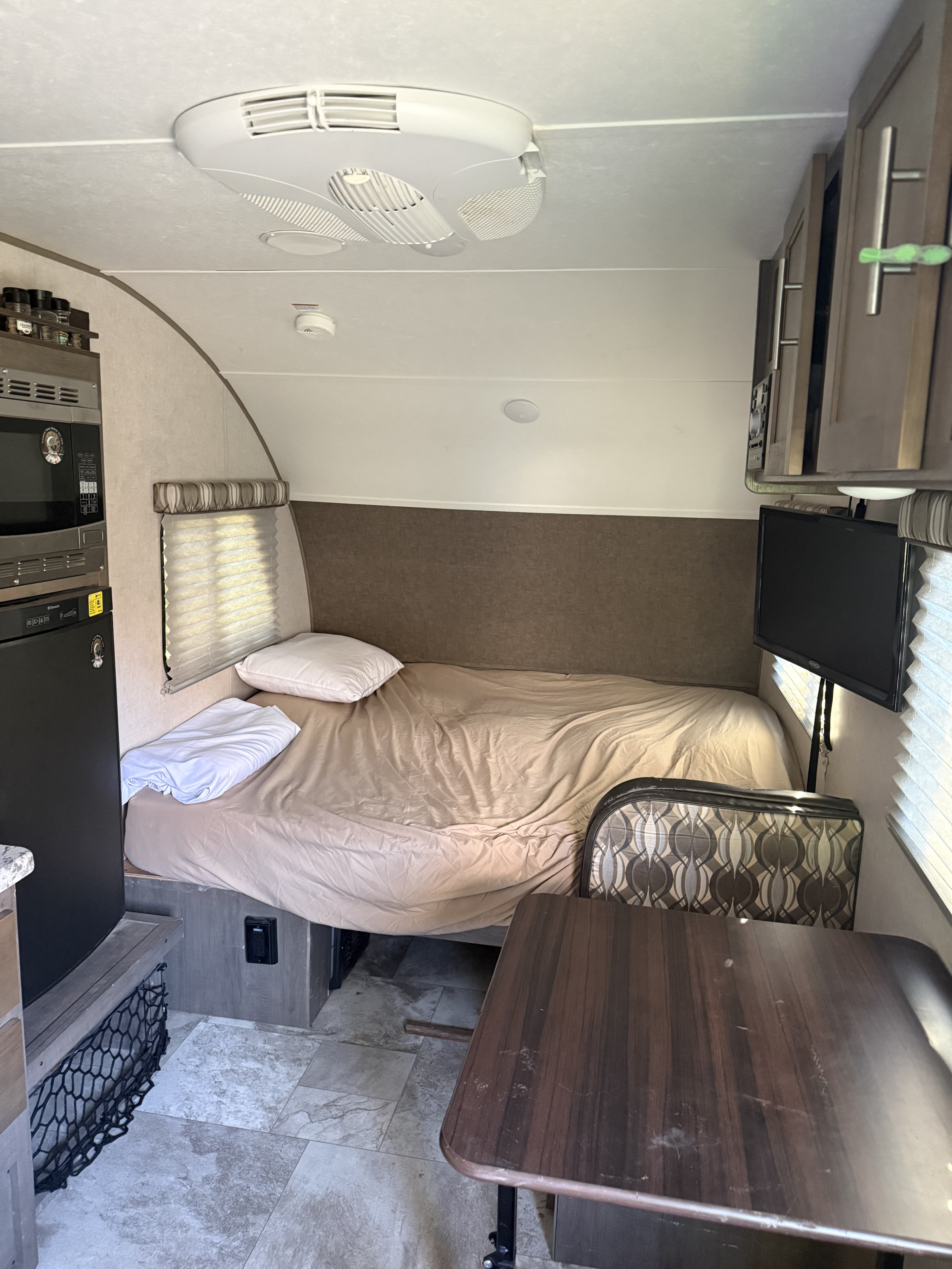 Interior of an **rv rental** featuring a compact living space: bed, dining area, kitchenette, and AC.. Forest River R Pod 2017