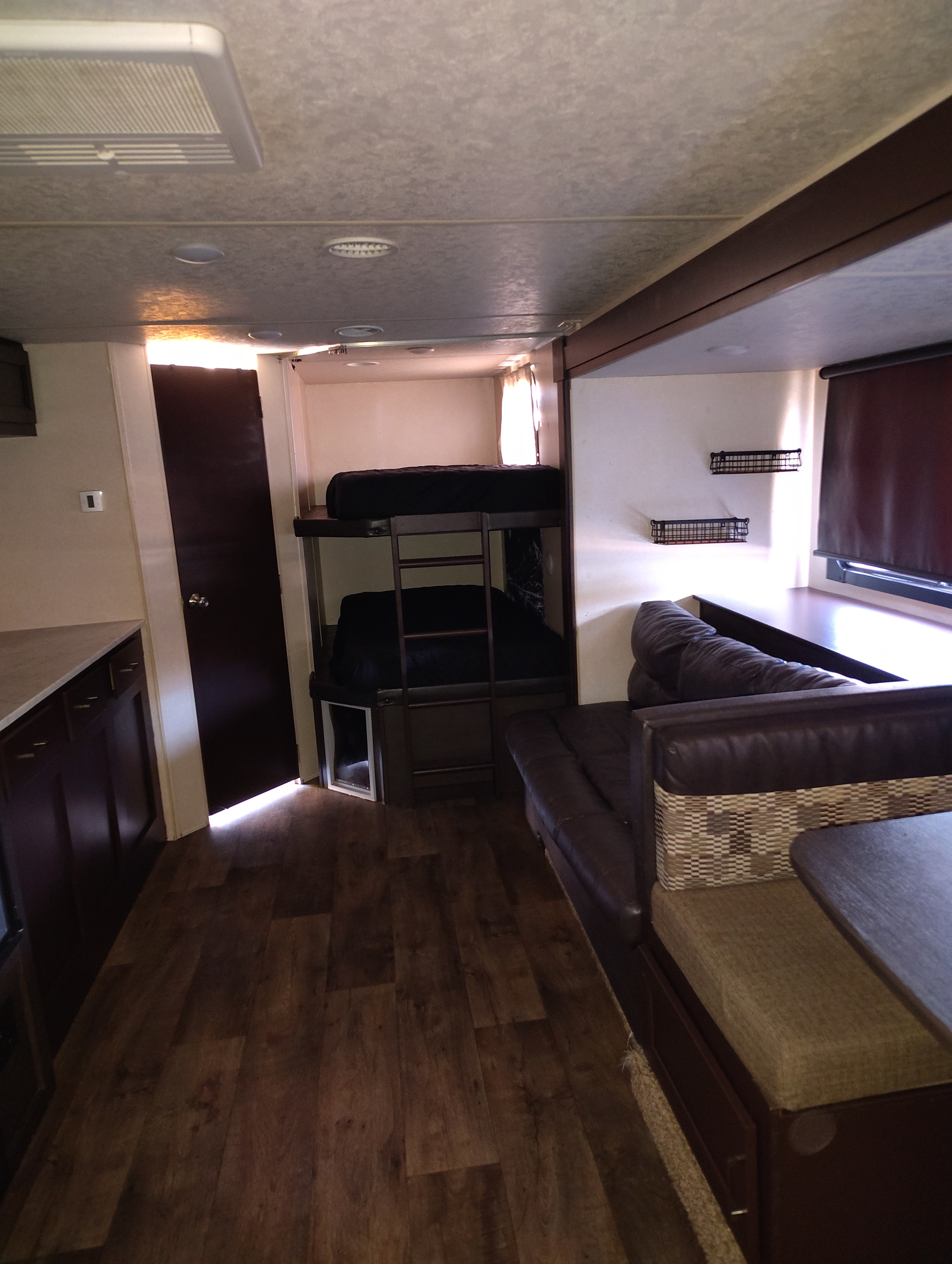 This RV rental interior features a cozy dinette, practical bunk beds, wood-look flooring, and ample living space.. Forest River Wildwood X-Lite 2019
