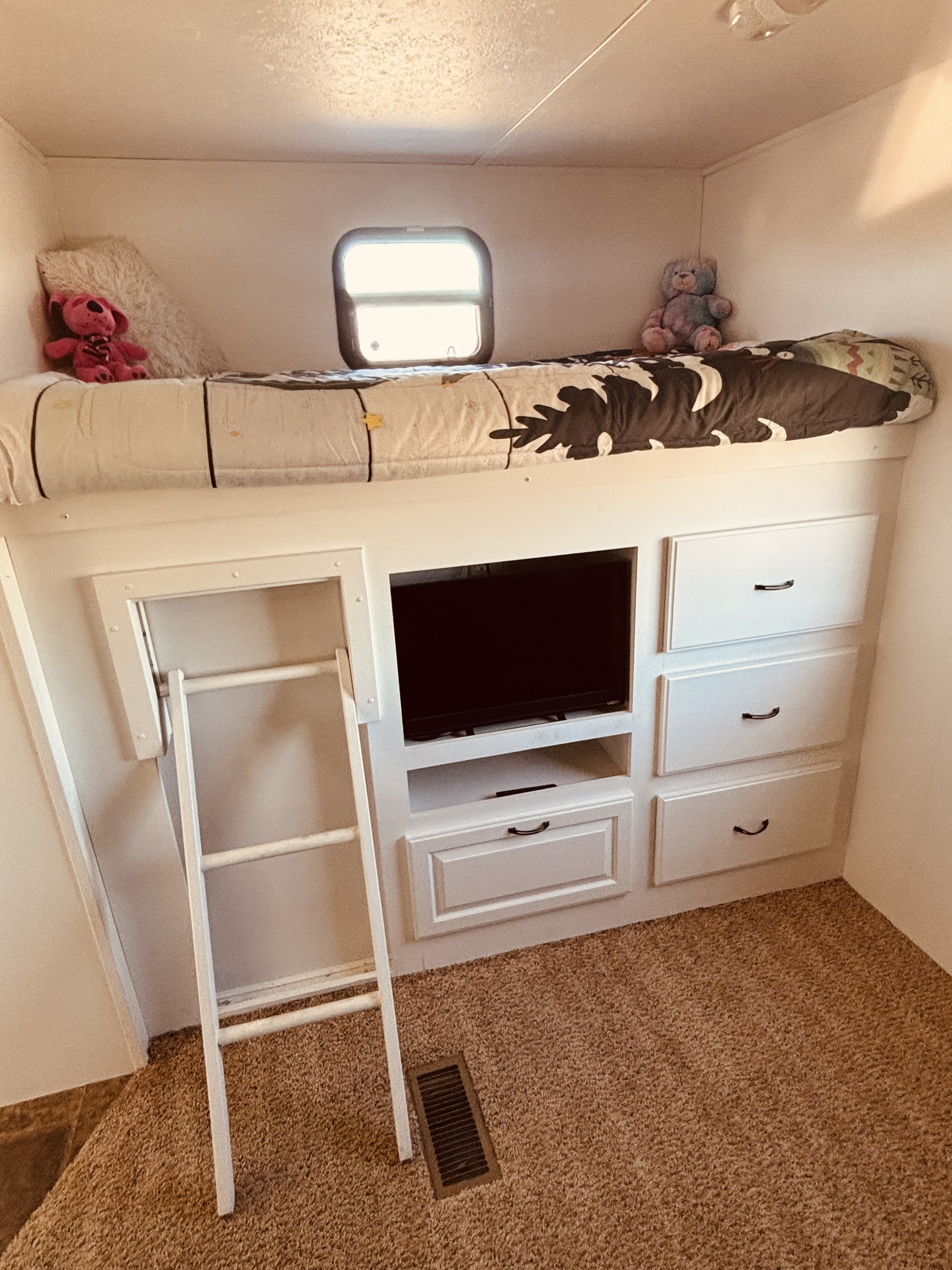 Cozy RV rental bunk bed area featuring a window, TV, ladder, and multiple storage drawers below. Perfect for kids.. Keystone RV Laredo 2013