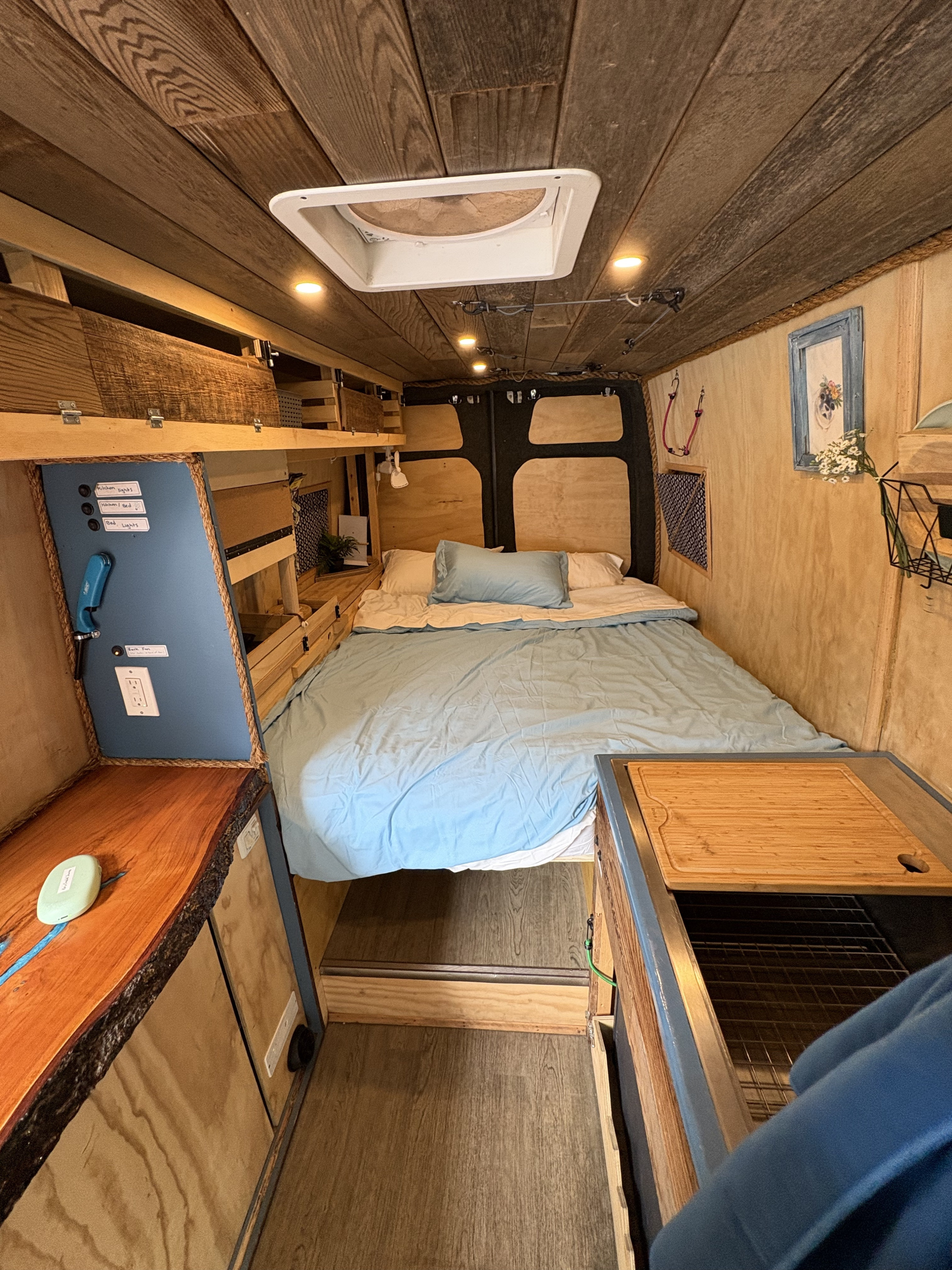 Explore this rustic rv rental interior featuring a comfy bed, wood-paneled ceiling, and a compact kitchen.. Mercedes-Benz Sprinter RV Motorhome Campervan 2011