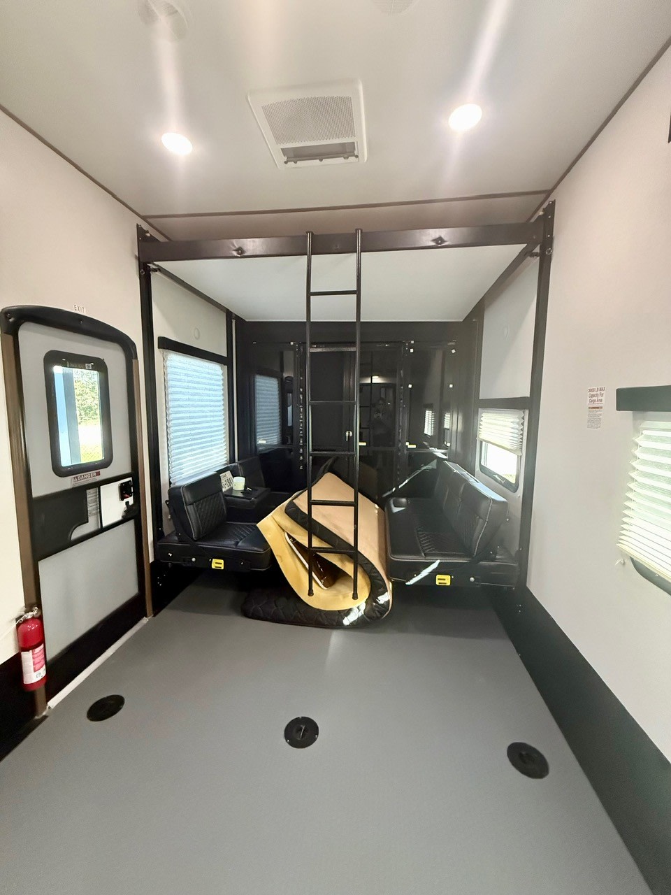 Spacious RV rental toy hauler interior featuring flexible seating, overhead bunk, and open floor space.. Keystone Fuzion 2020