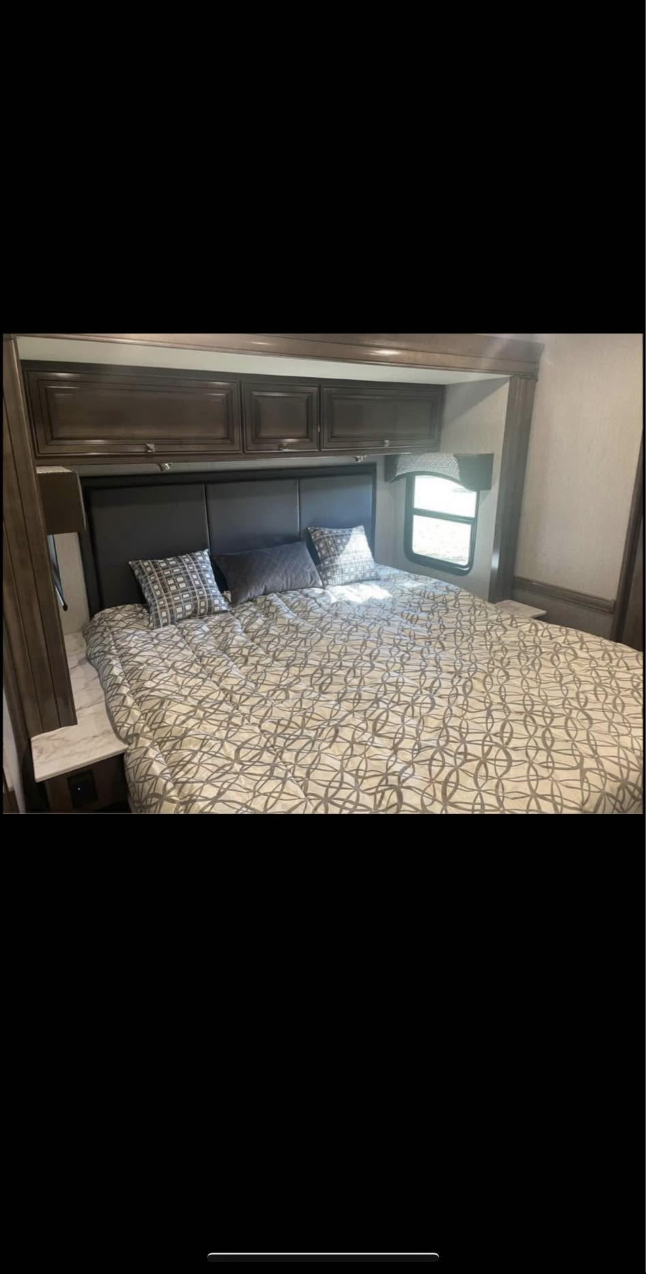 This RV rental bedroom features a comfy bed, overhead storage, side tables, and a window for relaxing trips.. Fleetwood Fortis 2021