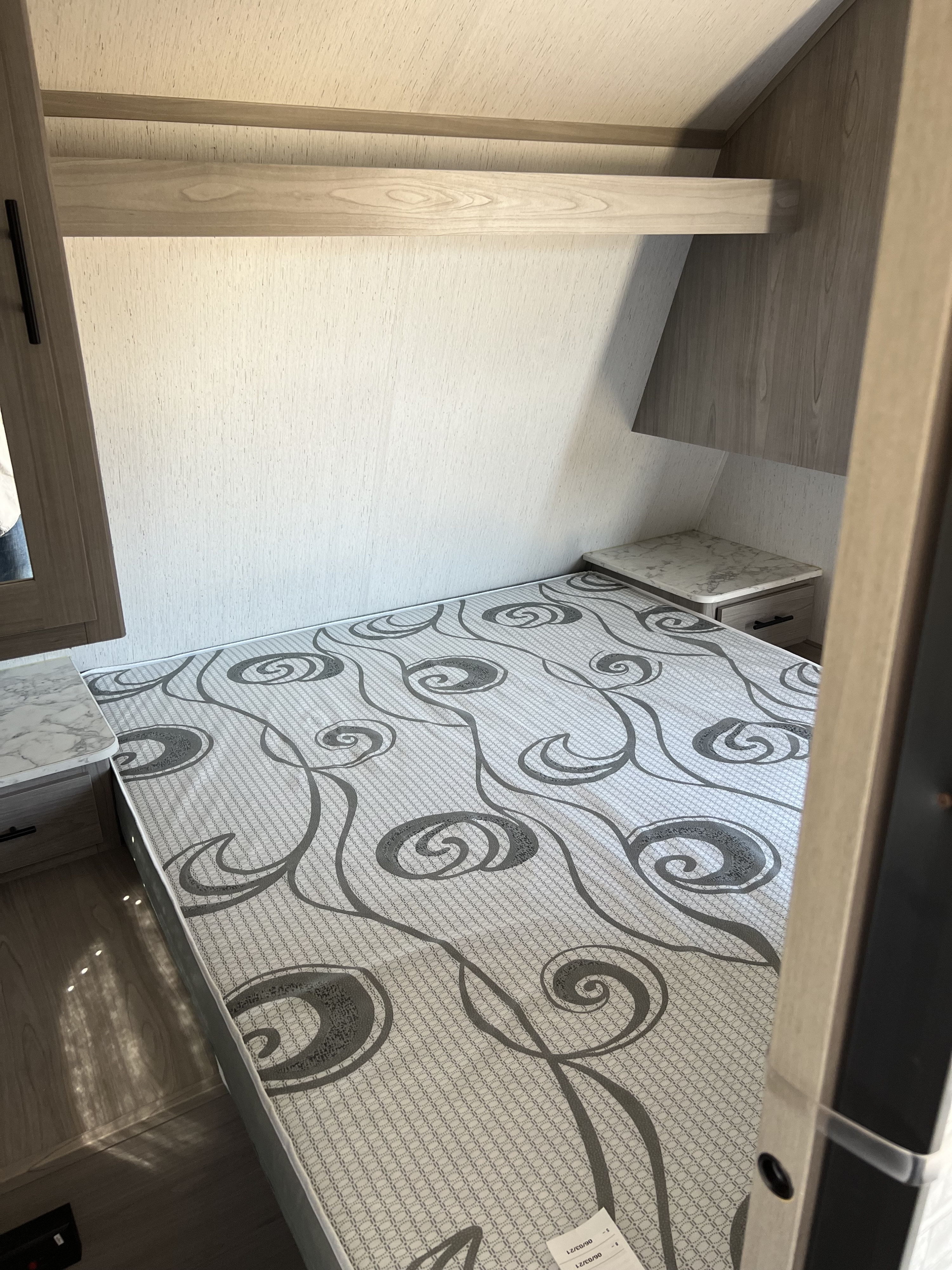 This RV rental's cozy bedroom features a patterned mattress, convenient side tables, and an overhead storage shelf.. Dutchmen Coleman Lantern 2022