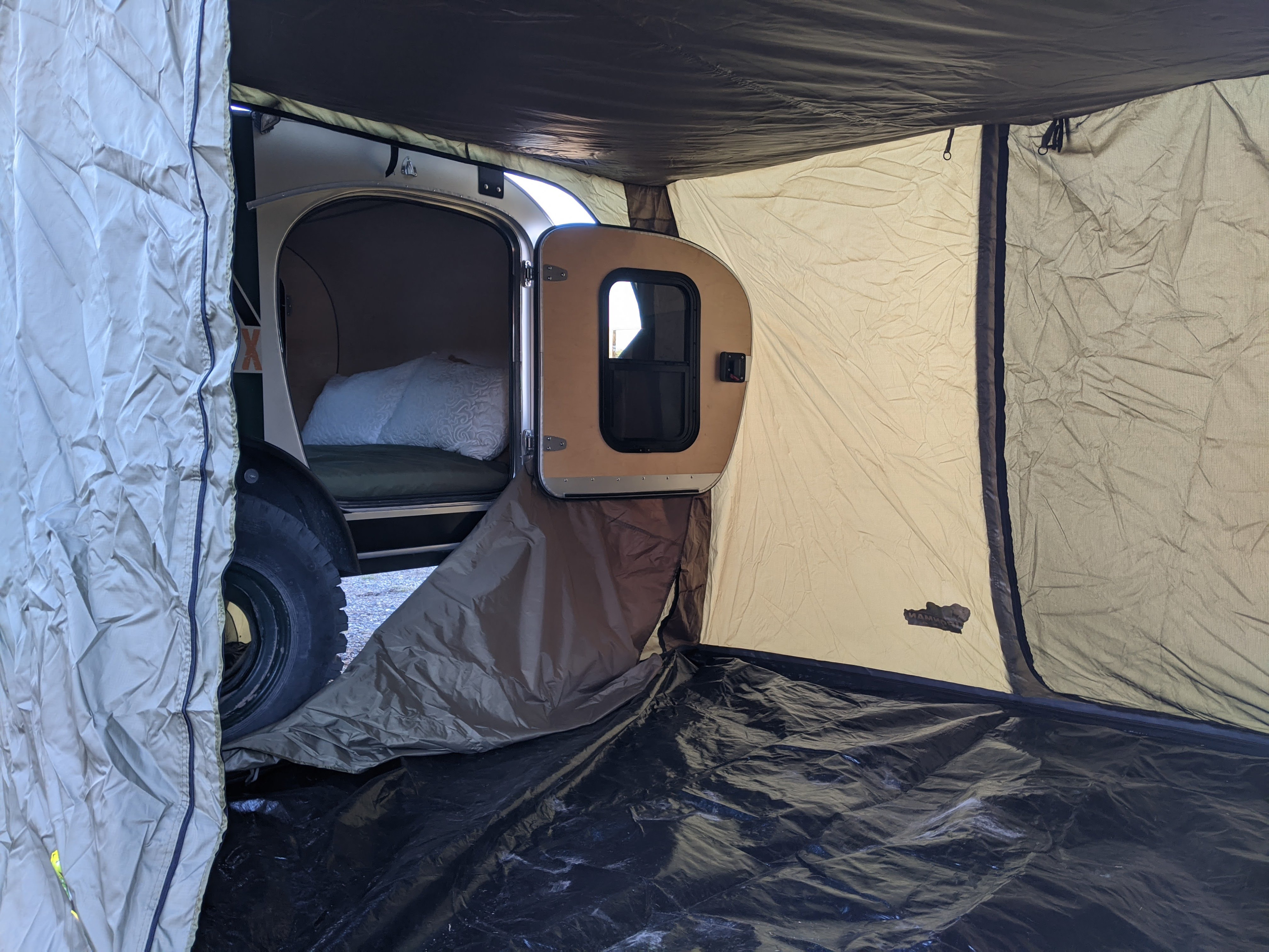 Teardrop camper's attached annex tent with an open door to the sleeping area, ideal for an RV rental adventure.. Vintage Overland Lawrence 2019