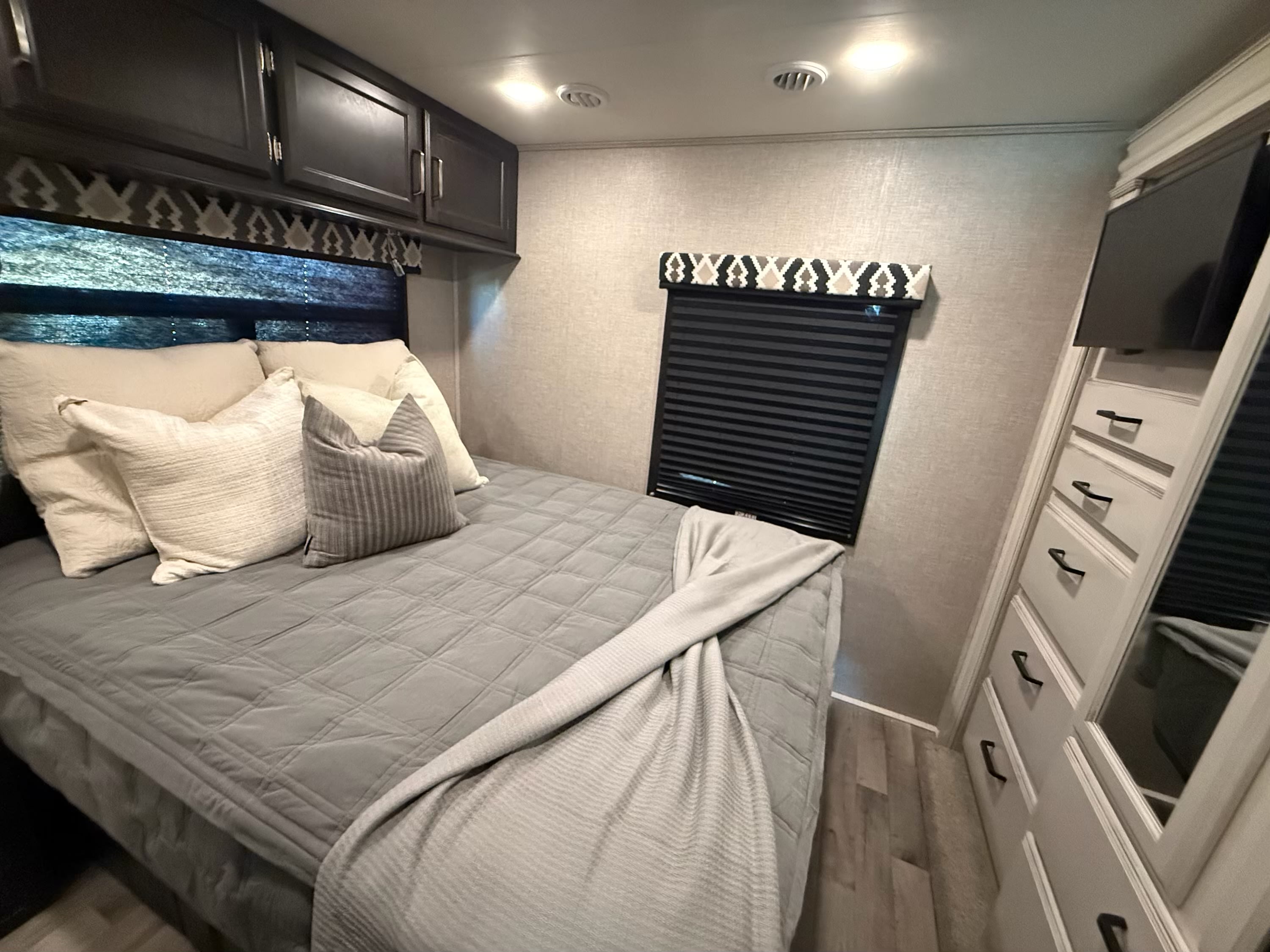 Cozy RV bedroom featuring a comfortable bed, overhead cabinets, and TV, perfect for your next RV rental getaway.. Entegra Coach Odyssey 2022