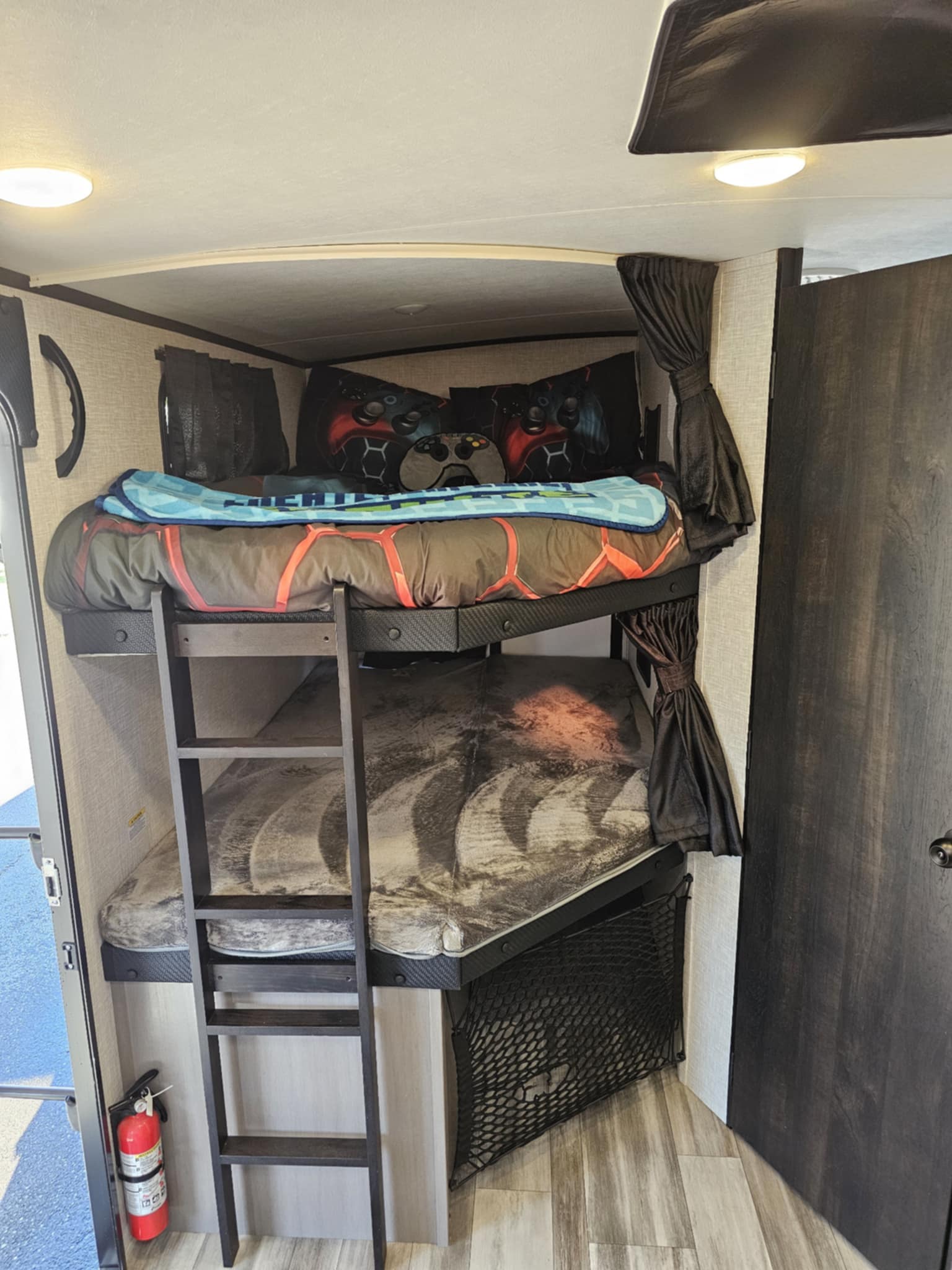 Cozy RV rental bunk beds with gaming-themed bedding, a ladder, and safety extinguisher. Ideal for family camping.. Jayco White Hawk 2024