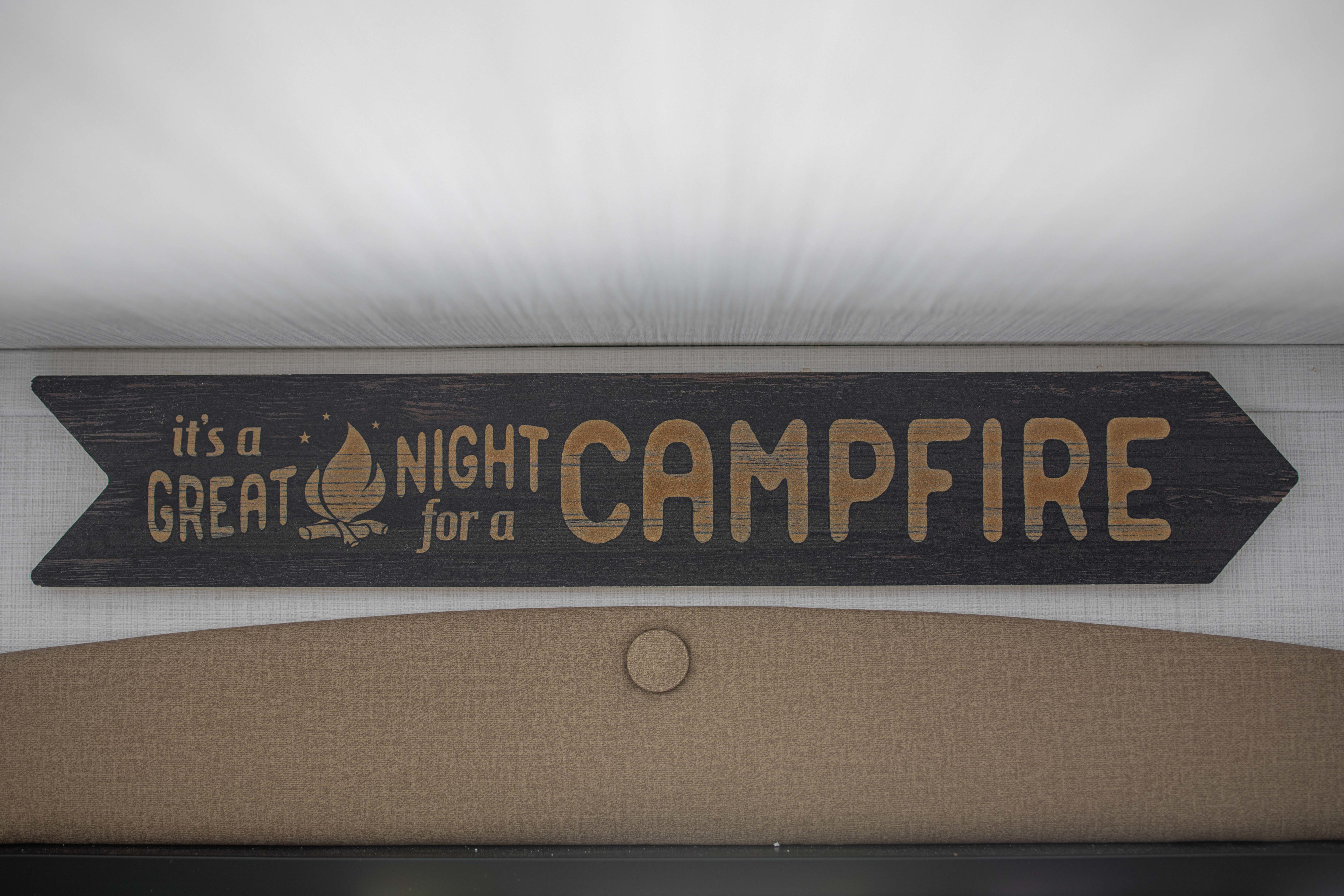 An RV rental interior features a dark wood "GREAT NIGHT for a CAMPFIRE" sign, perfect for camping adventures.. Keystone RV Bullet Classic 2025