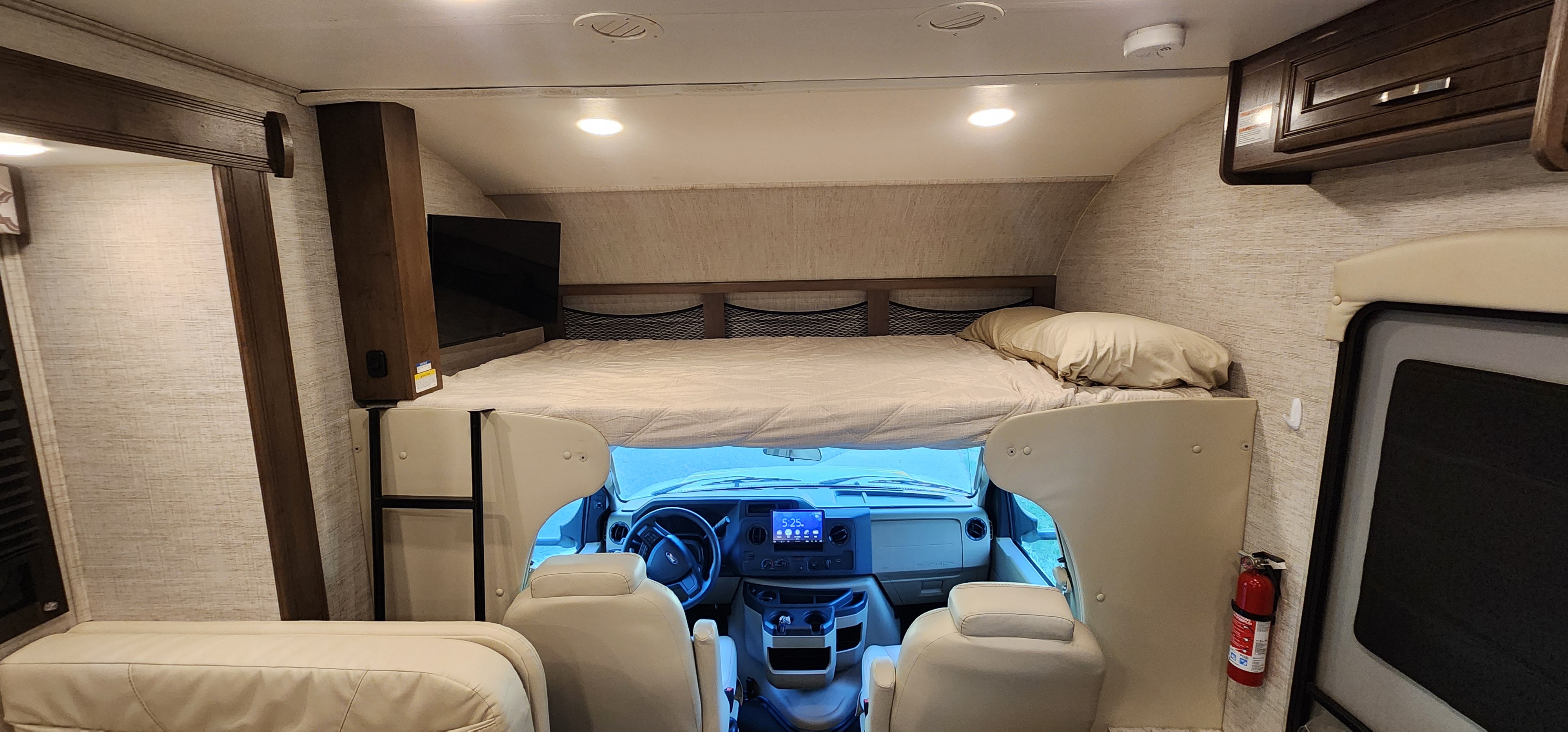 Spacious RV rental interior featuring a cab-over bed, driver's cockpit, and entertainment TV for comfortable travel.. Jayco 31F 2021