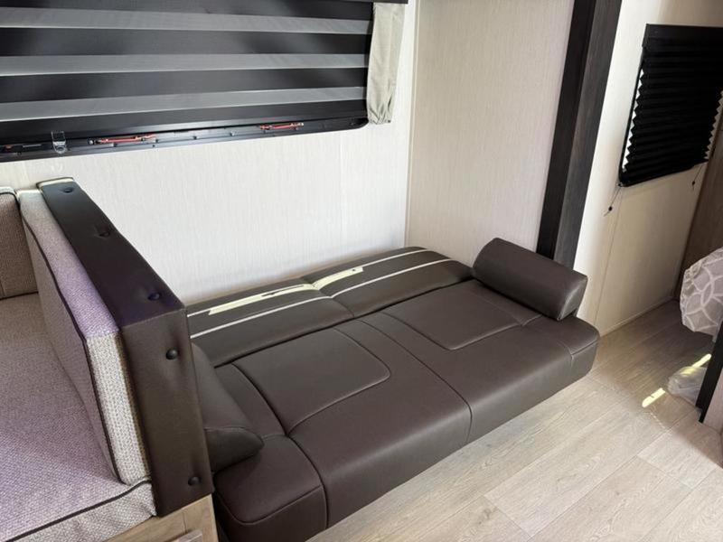 RV rental: A brown pull-out sofa bed in a compact RV interior, featuring window blinds, light wood flooring, and dinette seating.. Forest River Grey Wolf Black Label 2026