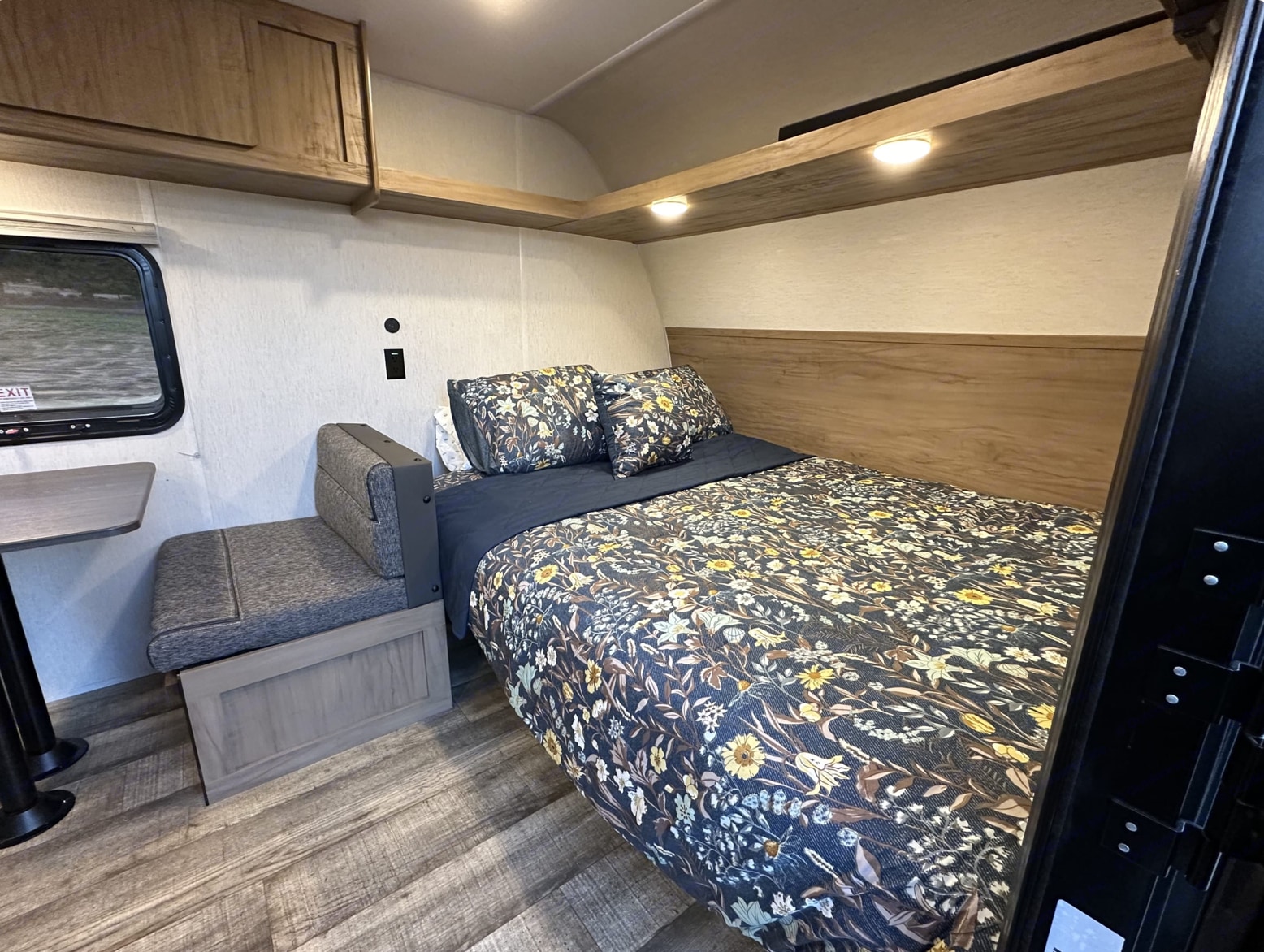 RV rental: interior bedroom featuring a floral patterned bed, small dinette, and wood cabinets.. Forest River Cherokee Wolf Den 16 EV 2024