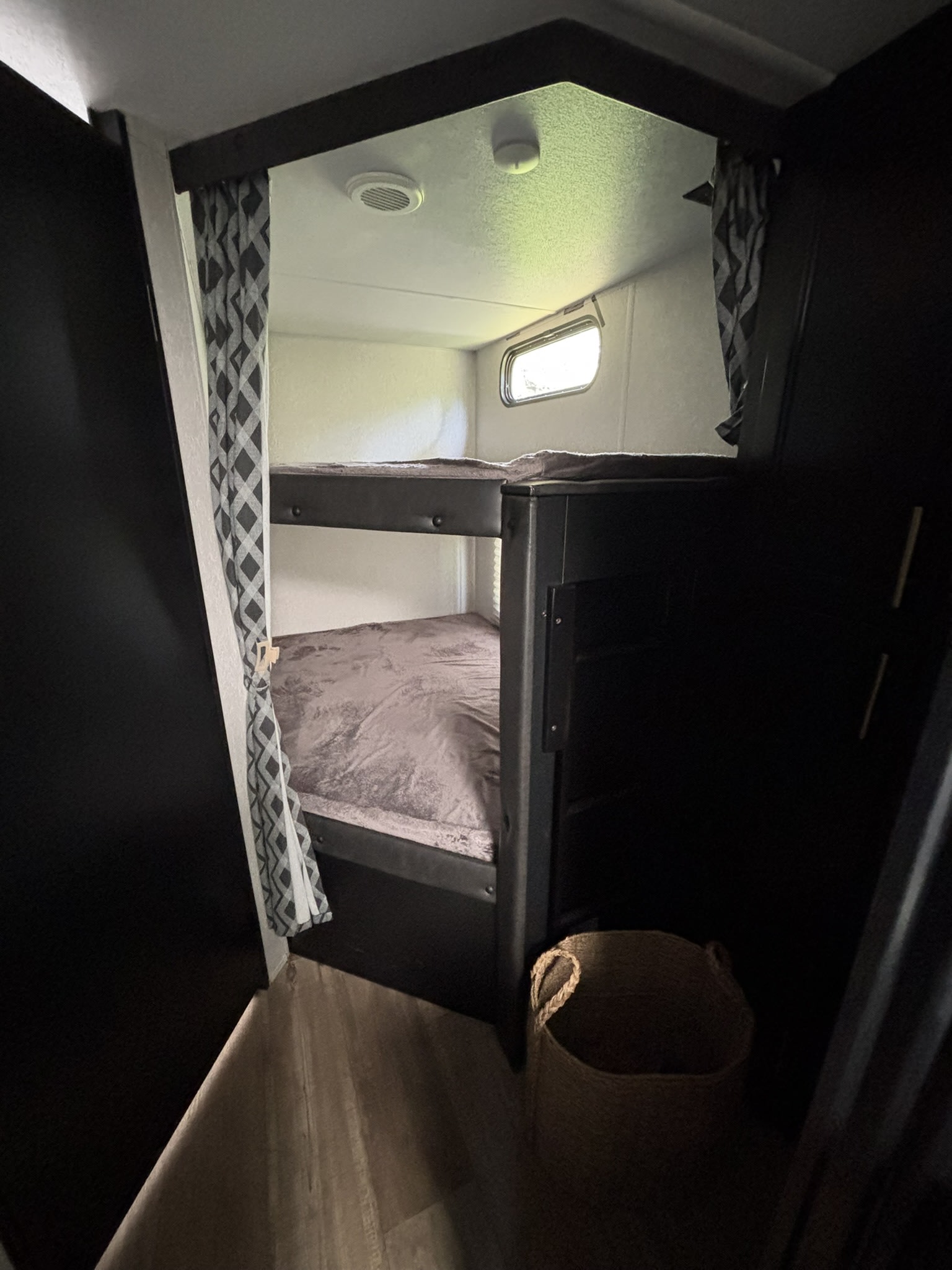 Inside an RV rental: cozy bunk beds with light bedding, a window, and patterned curtains for a comfortable sleep.. Forest River Cherokee Grey Wolf 2022