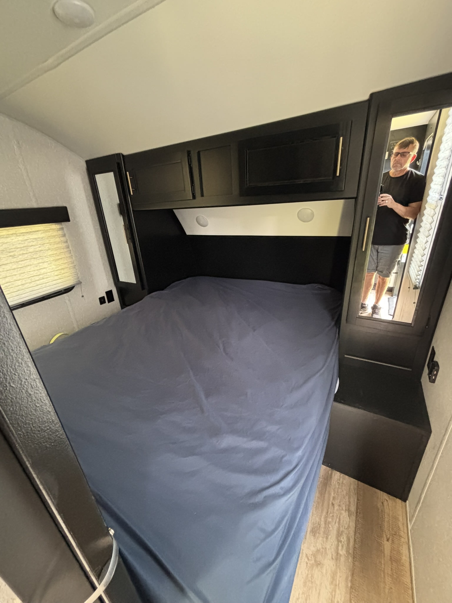 Cozy rv rental bedroom interior with dark bed, black cabinets, and a reflection in the mirror. Ideal for travel accommodation.. Forest River Cherokee Grey Wolf 2022