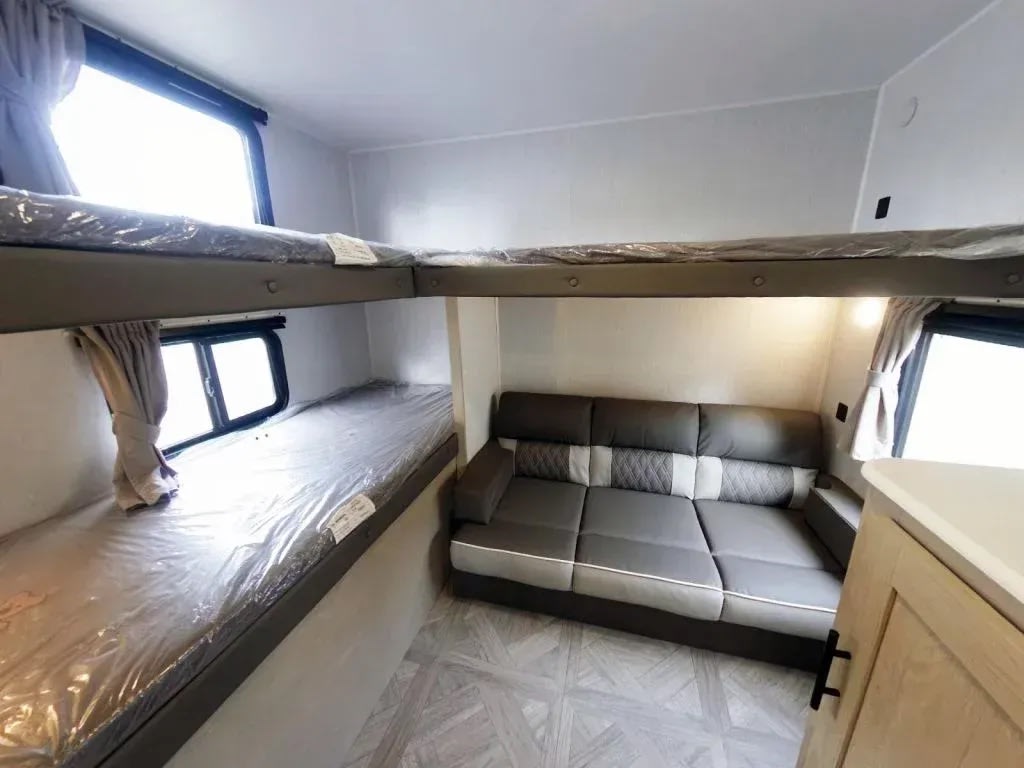 Spacious rv rental bunkhouse interior, featuring protected bunk beds, a comfy sofa, and bright windows.. Forest River Evo 2750QBX 2023
