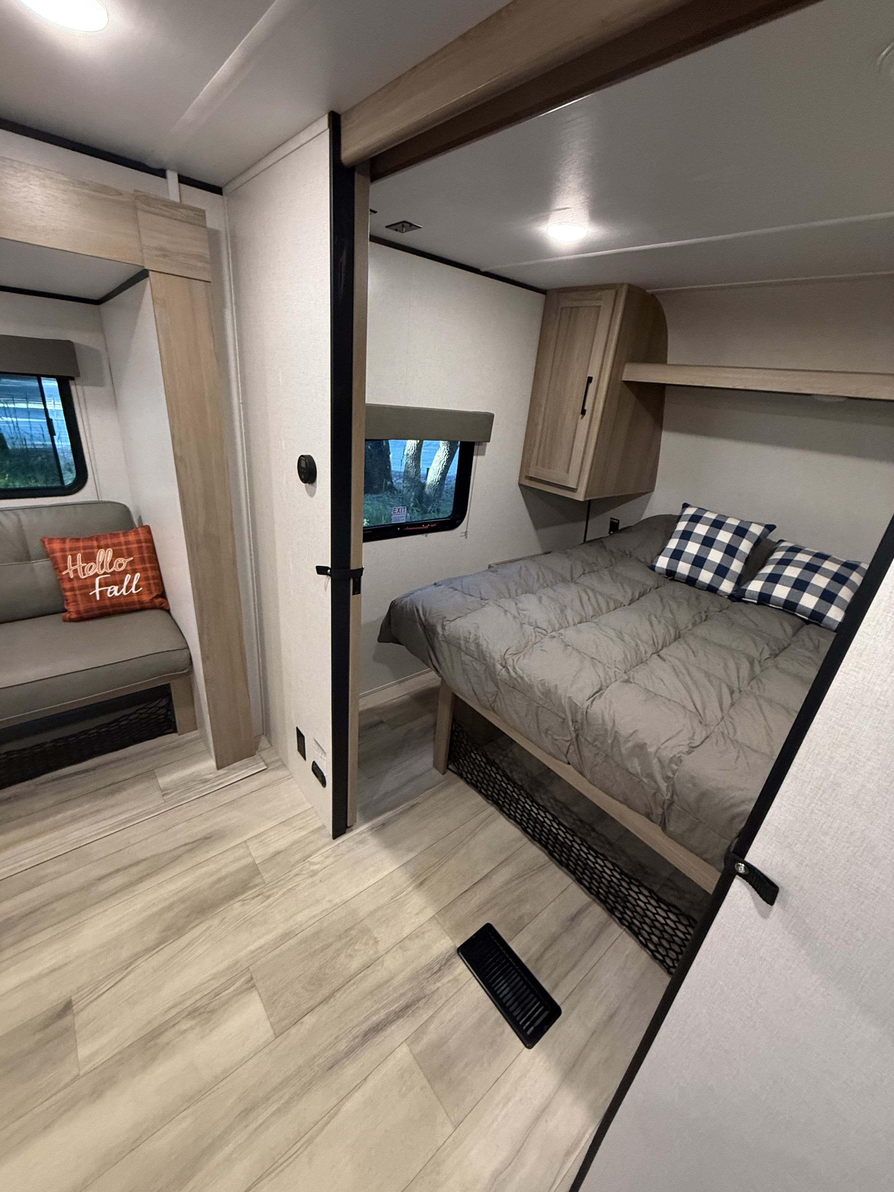 Step inside this modern RV rental! Features include a cozy bedroom with storage, a sofa, and light wood-look flooring.. Keystone RV Coleman Light 2025
