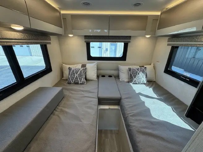RV rental interior showcasing a comfortable sleeping area with two twin beds, central console, and overhead storage.. Thor axis 2026