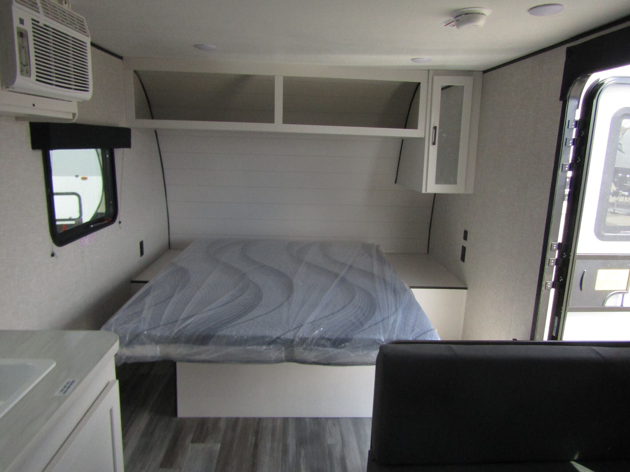 RV rental interior: A clean bed with new mattress, AC unit, overhead storage, and light-toned walls create a comfortable space.. Jayco Jay Flight SLX 2025