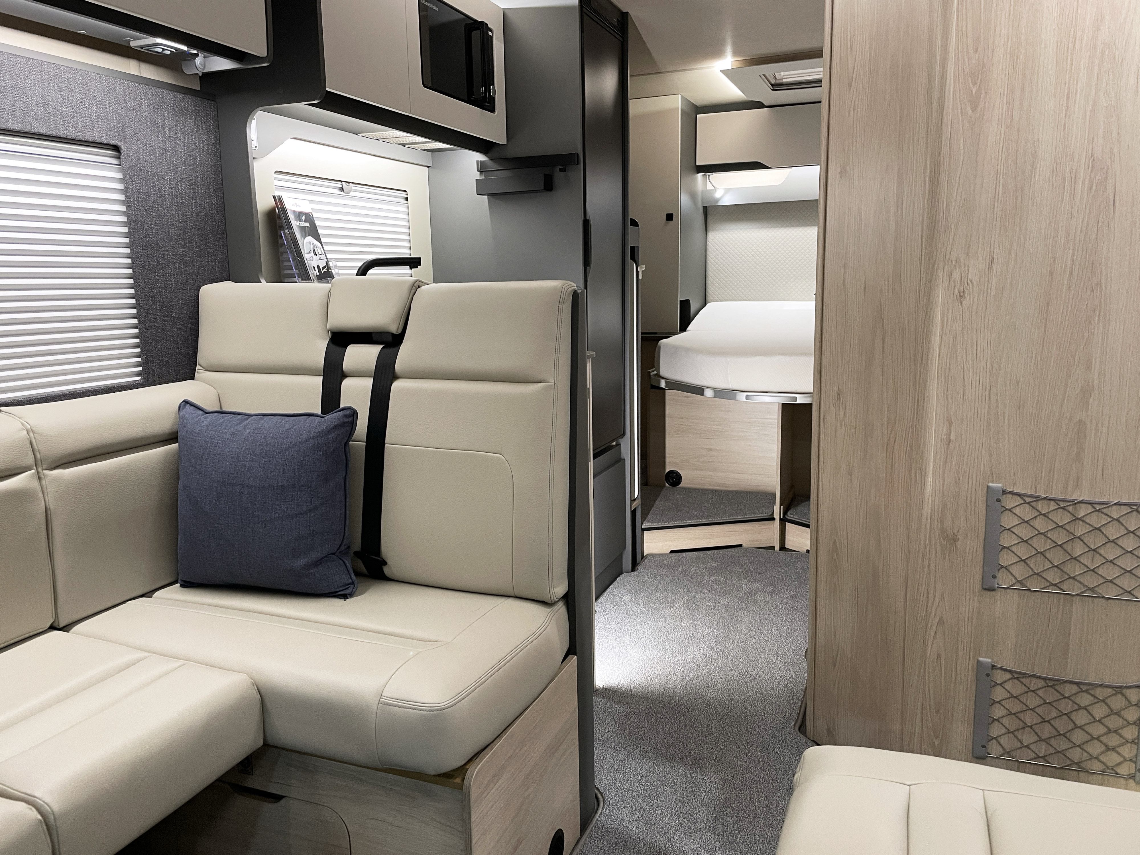 Comfortable rv rental interior featuring an L-shaped sofa, microwave, and cozy bedroom. Ideal for road trips and travel.. Auto-Trail F74 2026