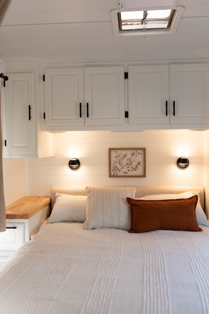 Cozy RV rental bedroom with modern white cabinets, warm lighting, and soft bedding for a comfortable travel experience.. Forest River Sunseeker LE 2006