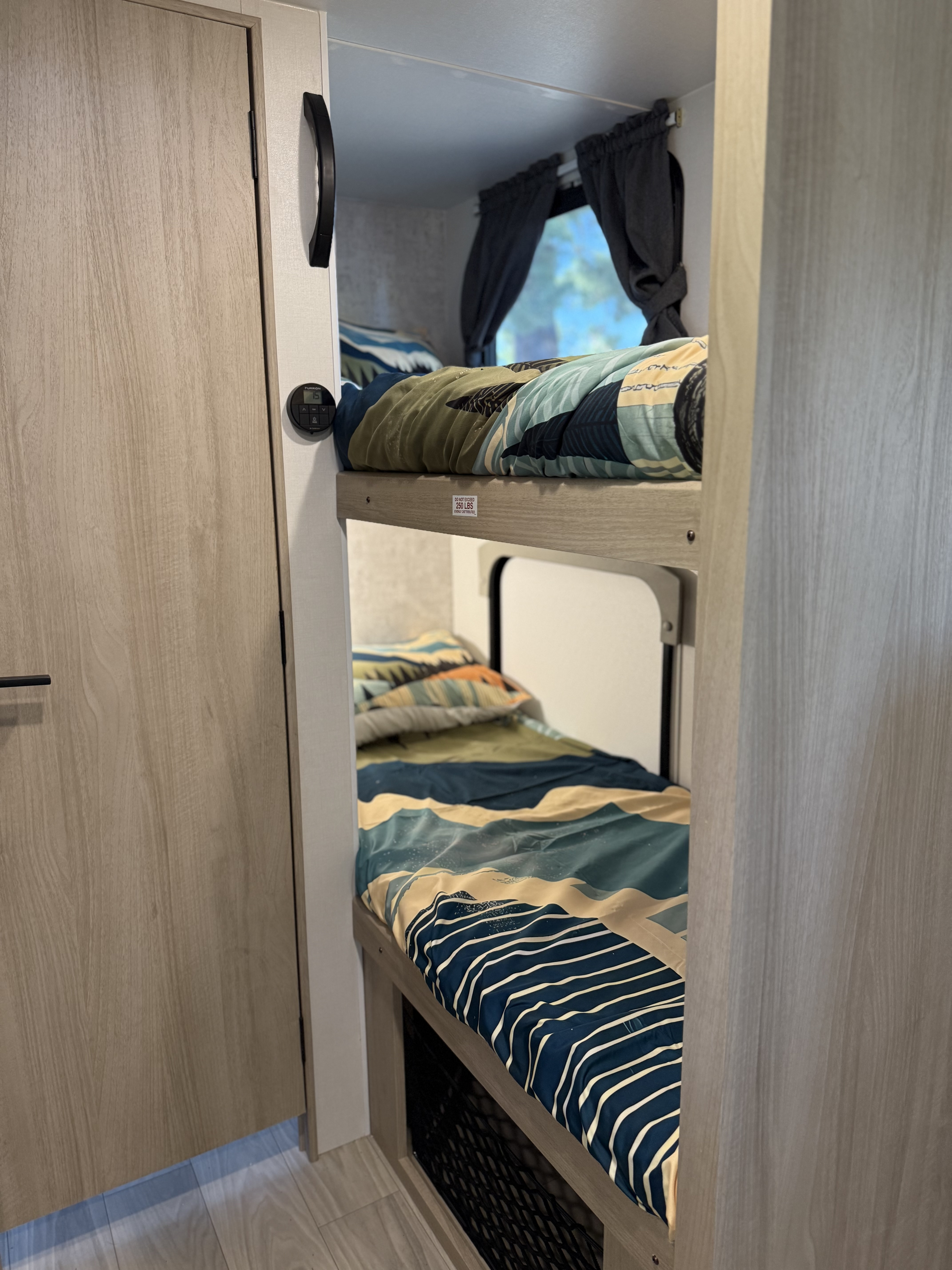 Cozy bunk beds in an RV rental, featuring mountain-themed bedding, window with curtains, and climate control for comfort.. Winnebago Micro Minnie 2100BH 2025