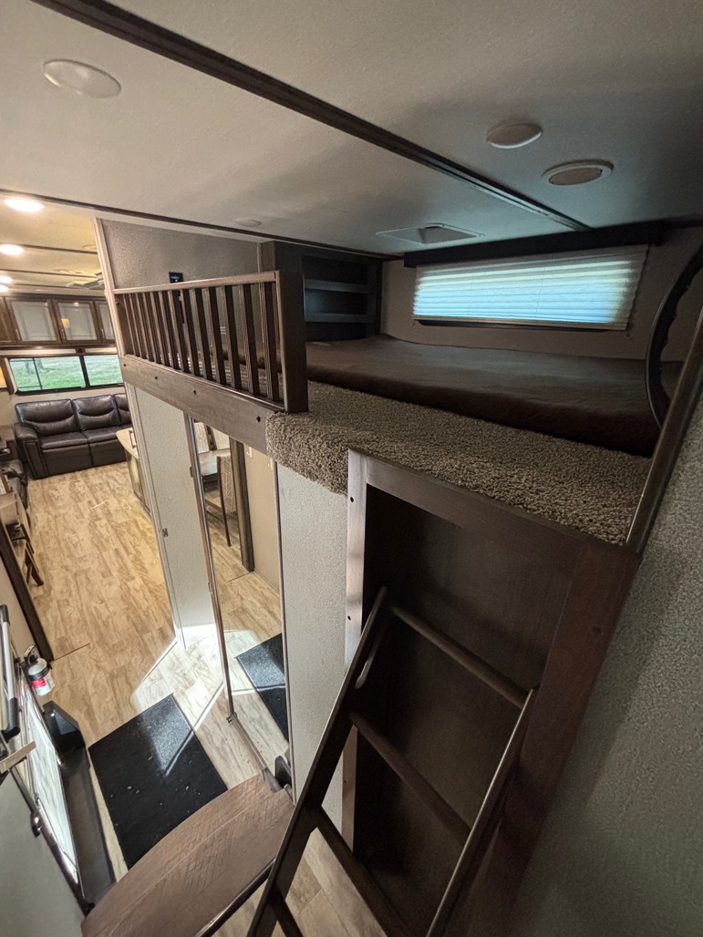 This RV rental's clever design features a cozy loft sleeping area, accessible by a sturdy ladder, overlooking the main living space.. Grand Design Solitude 2021