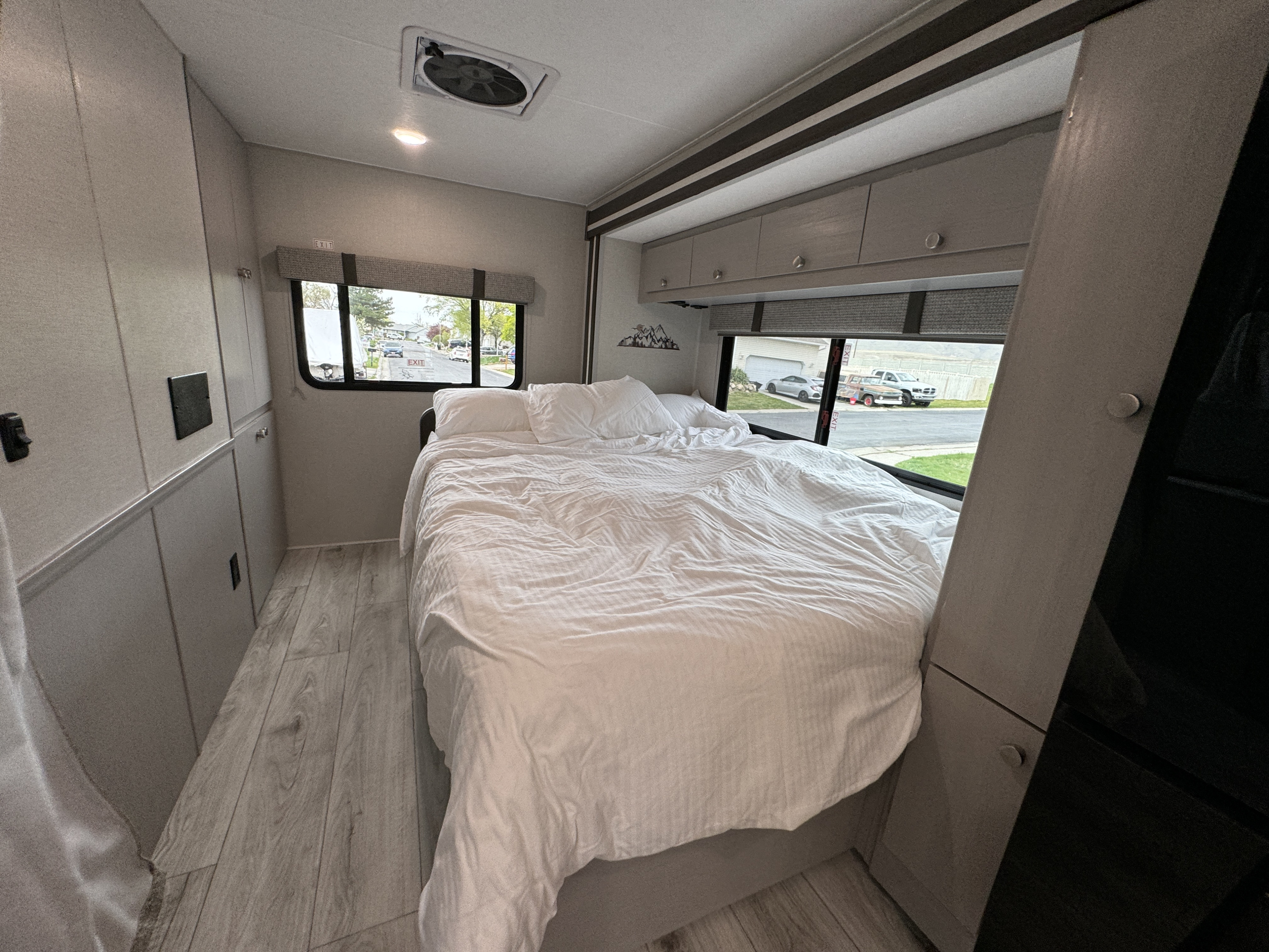 Comfortable RV rental bedroom with a large bed, overhead storage, and a street view, offering a cozy retreat on your travels.. Forest River Coachmen Freelander 2026