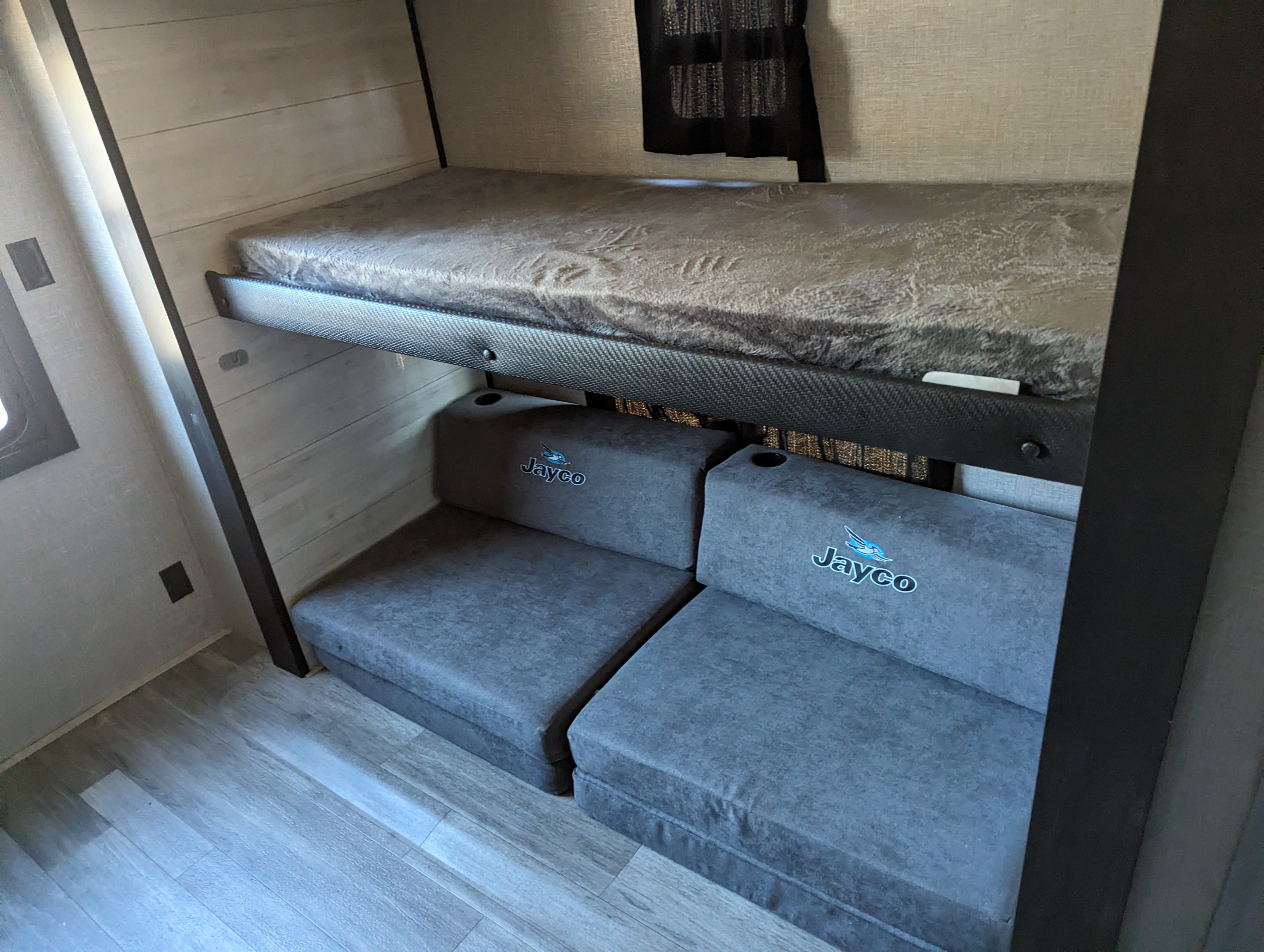 Inside an RV rental: a cozy bunk bed with soft mattress and versatile Jayco modular seating below, perfect for travel.. Jayco Jay Flight 2022