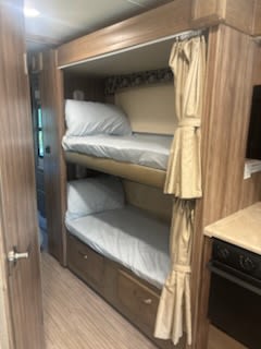 Inside this RV rental, comfortable bunk beds with light blue sheets and privacy curtains offer extra sleeping space.. Jayco Greyhawk Prestige 2019