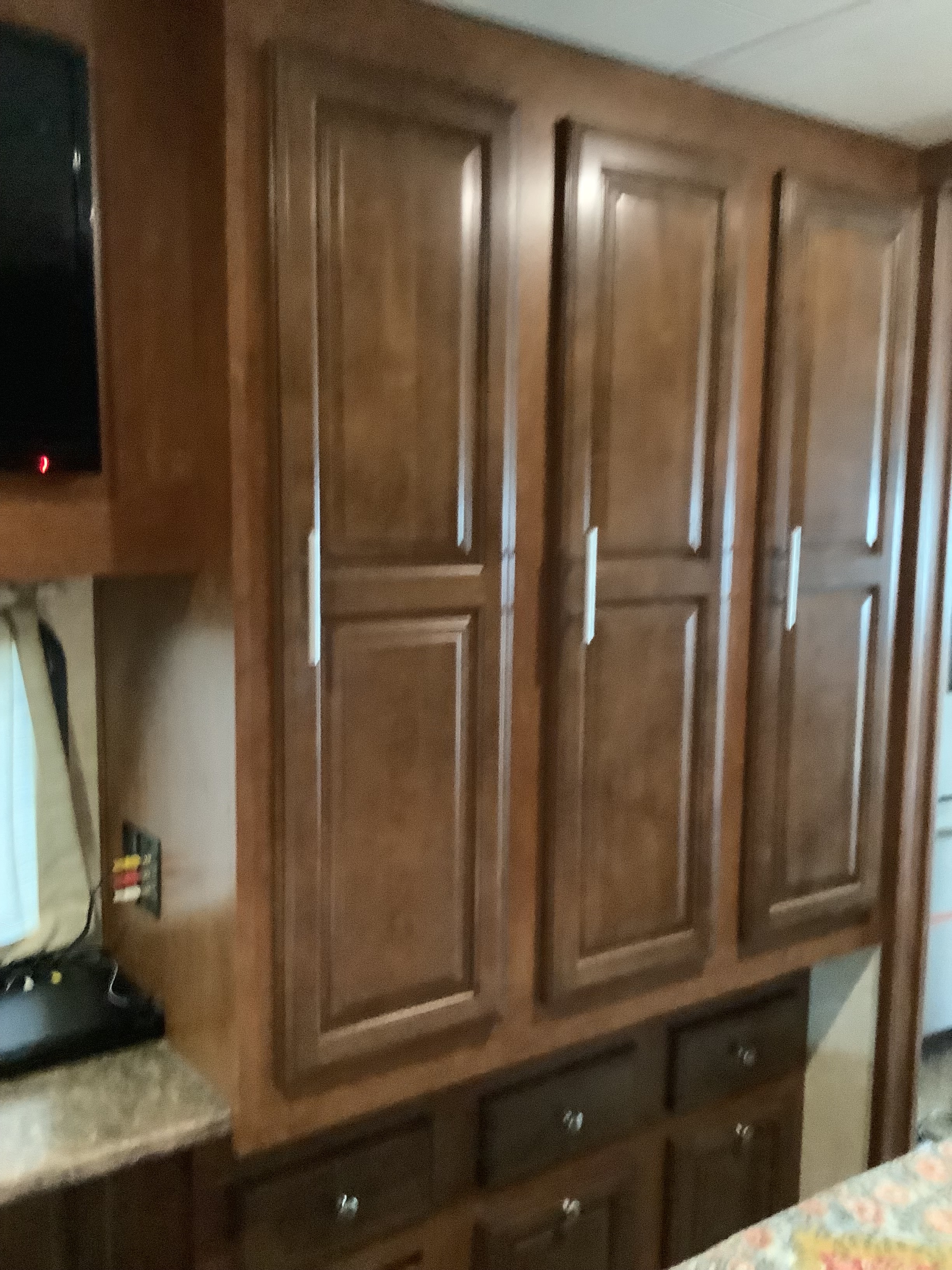 RV rental interior featuring rich wooden cabinets, drawers, and a TV area, offering a functional and cozy living space.. Georgetown XL 2015