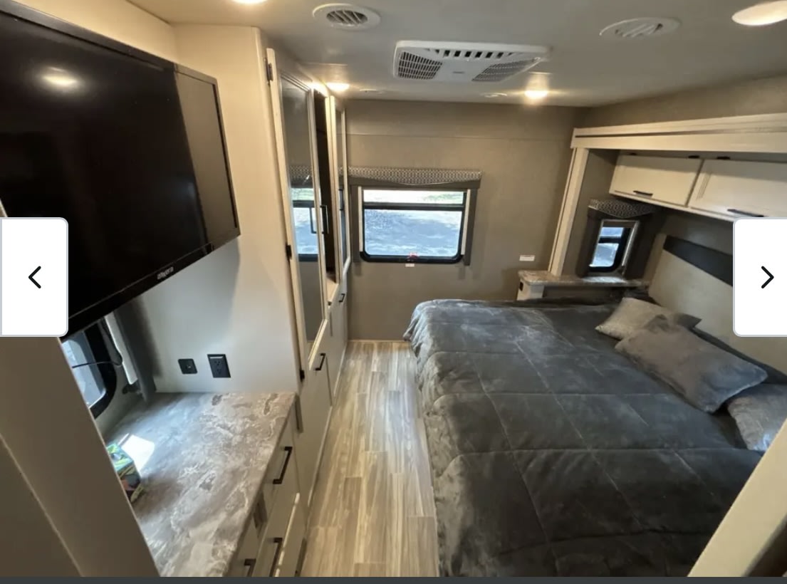 Comfortable RV rental bedroom with a cozy bed, TV, window, and ample storage for your travels.. Thor A.C.E. 2021