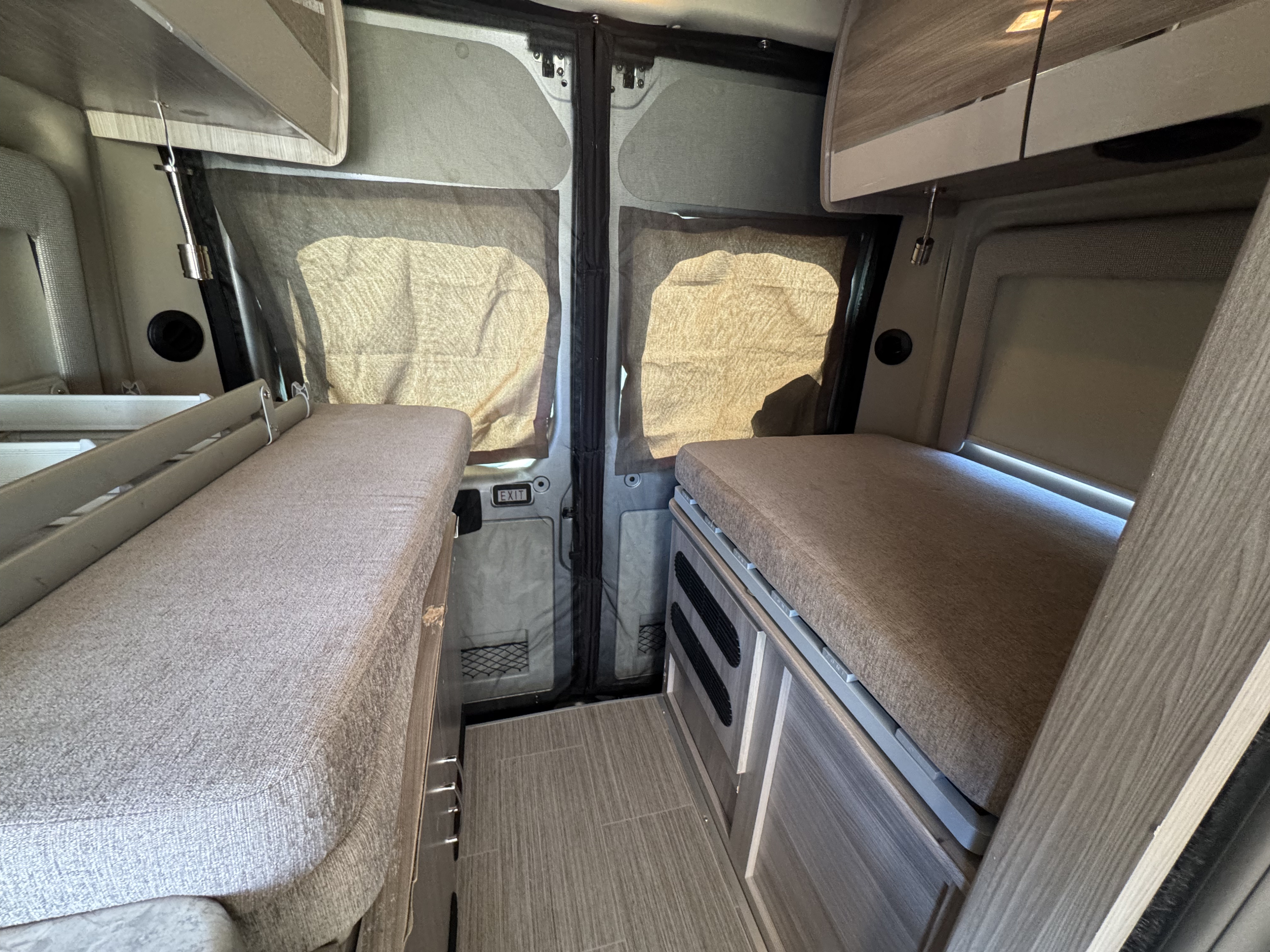 RV rental interior: Twin beds, central aisle, and screened back doors create a cozy camper van sleeping area.. Dodge Ram 1500 2022