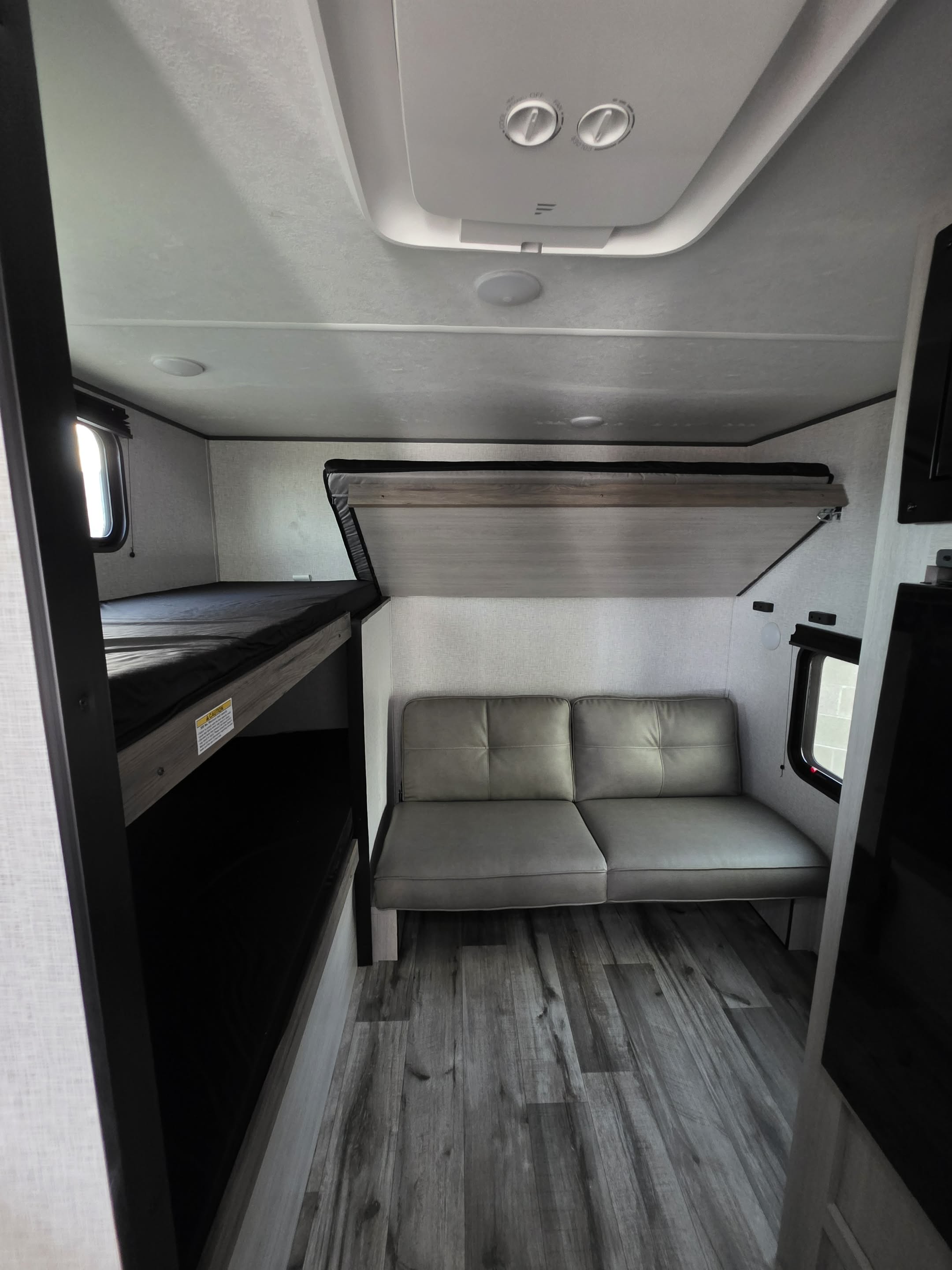 RV rental interior showcasing bunk beds, a comfortable sofa with an overhead fold-up bunk, and wood-look flooring.. CrossRoads Zinger ZR18QB26 2026